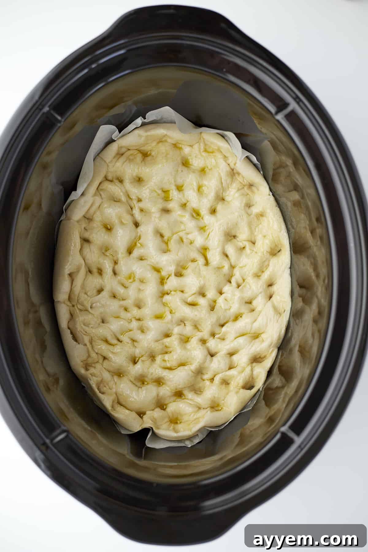 dinner rolls that have been partially baked and pressed down with fingers in a slow cooker, creating dimples