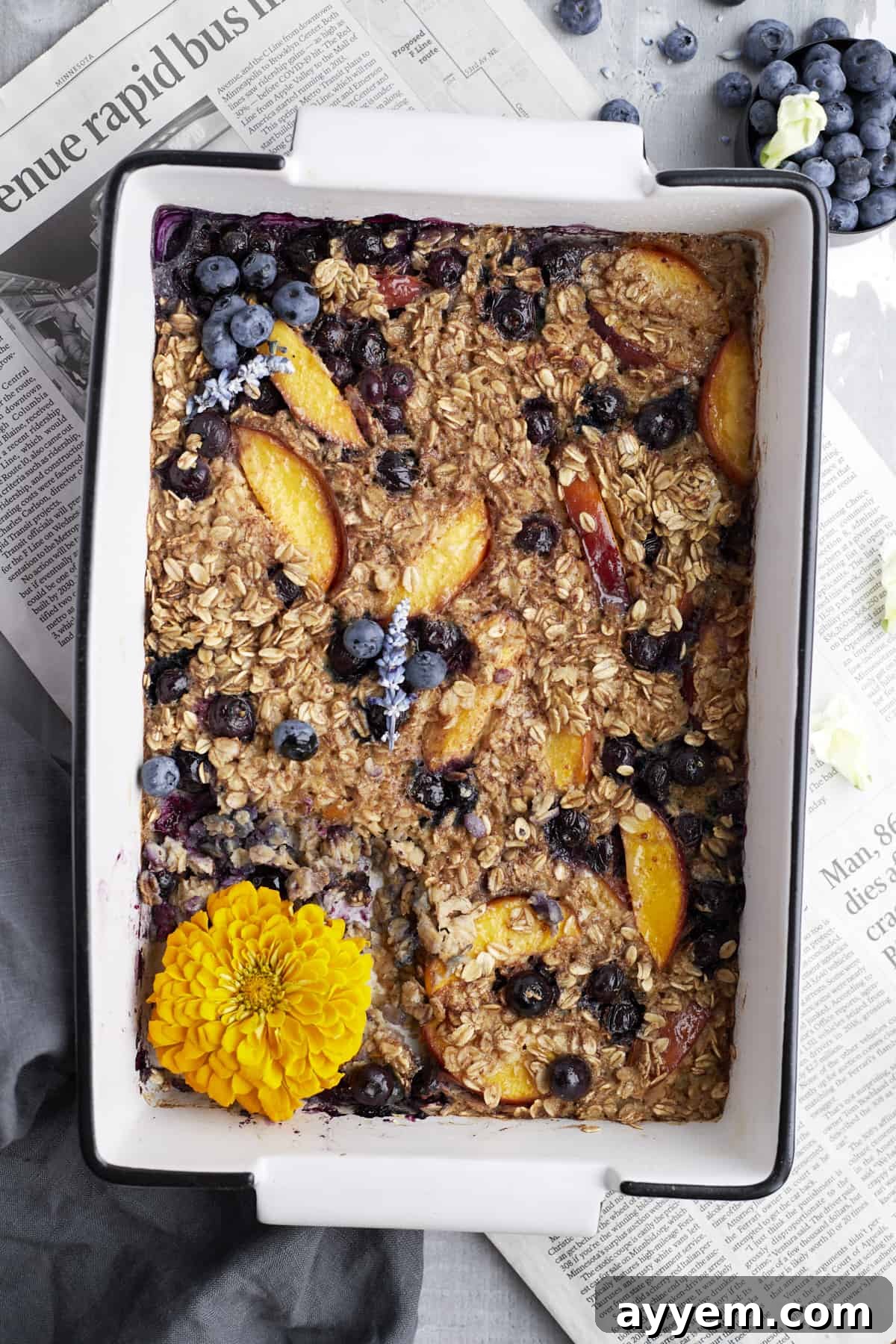 Overhead image of peach blueberry baked oats in a baking dish over newspaper
