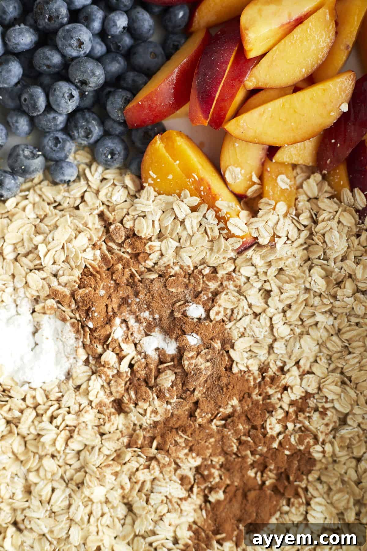 Closeup image of peaches, blueberries, oats, cinnamon, and sugar to make peach blueberry baked oats