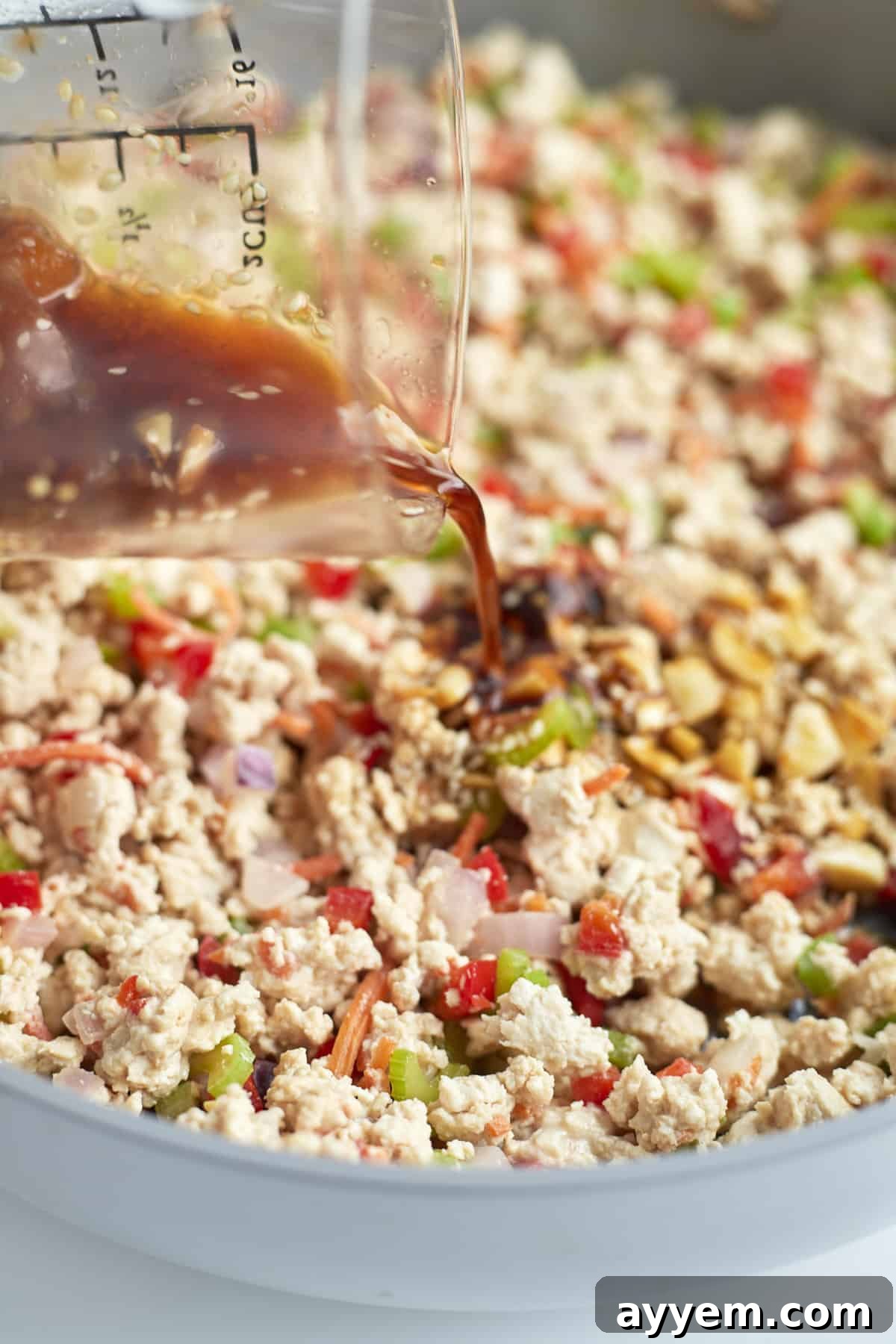 Asian chicken and vegetables being actively stirred in a skillet, coated in the delicious apricot sauce.