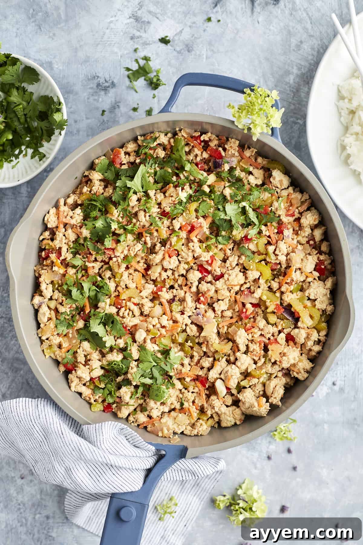 Overhead image of a skillet filled with freshly cooked Asian chicken, garnished with crushed peanuts and cilantro.