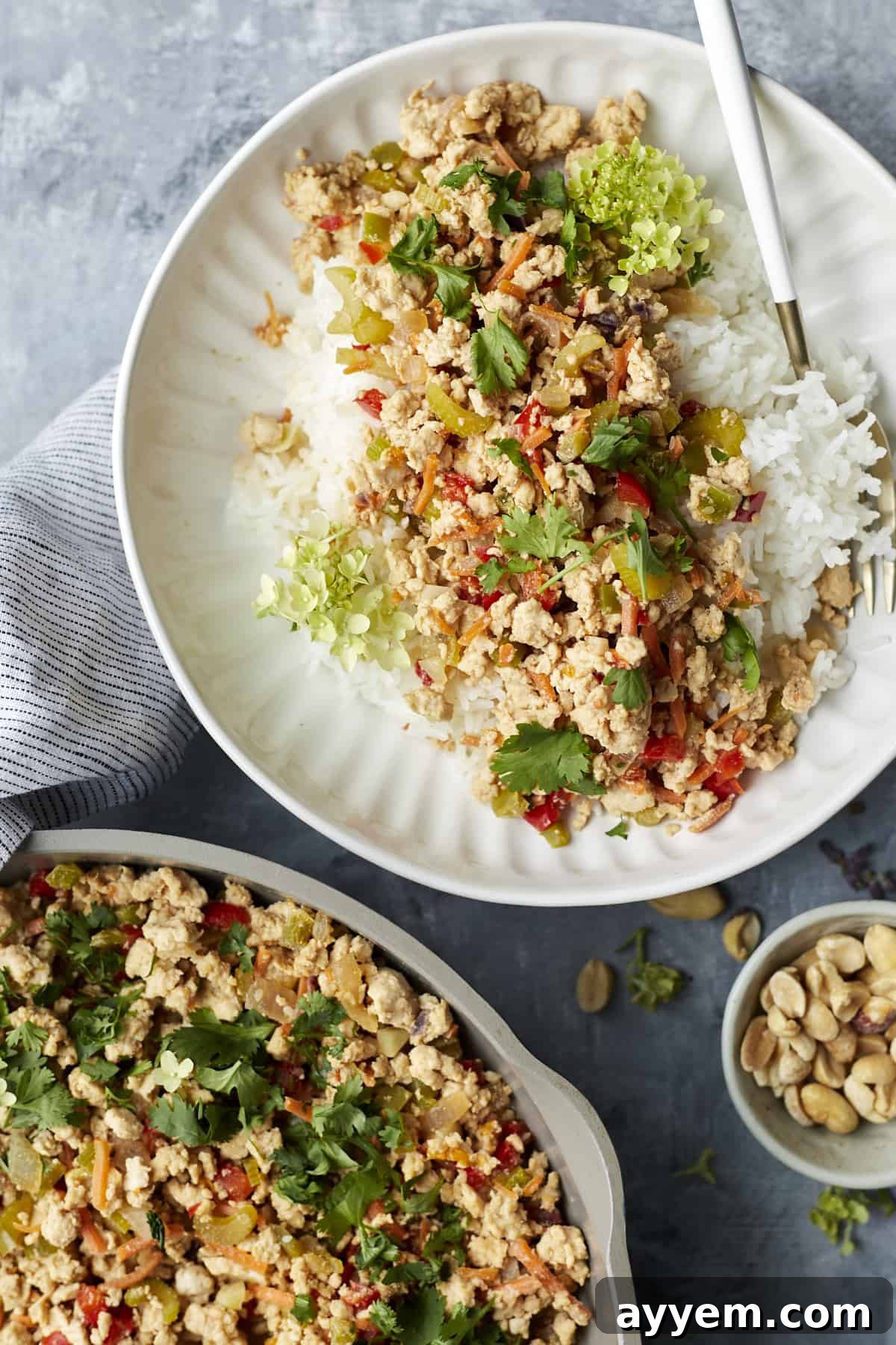 A plate with Asian chicken and rice next to a skillet full of the chicken mixture, showcasing meal prep potential.