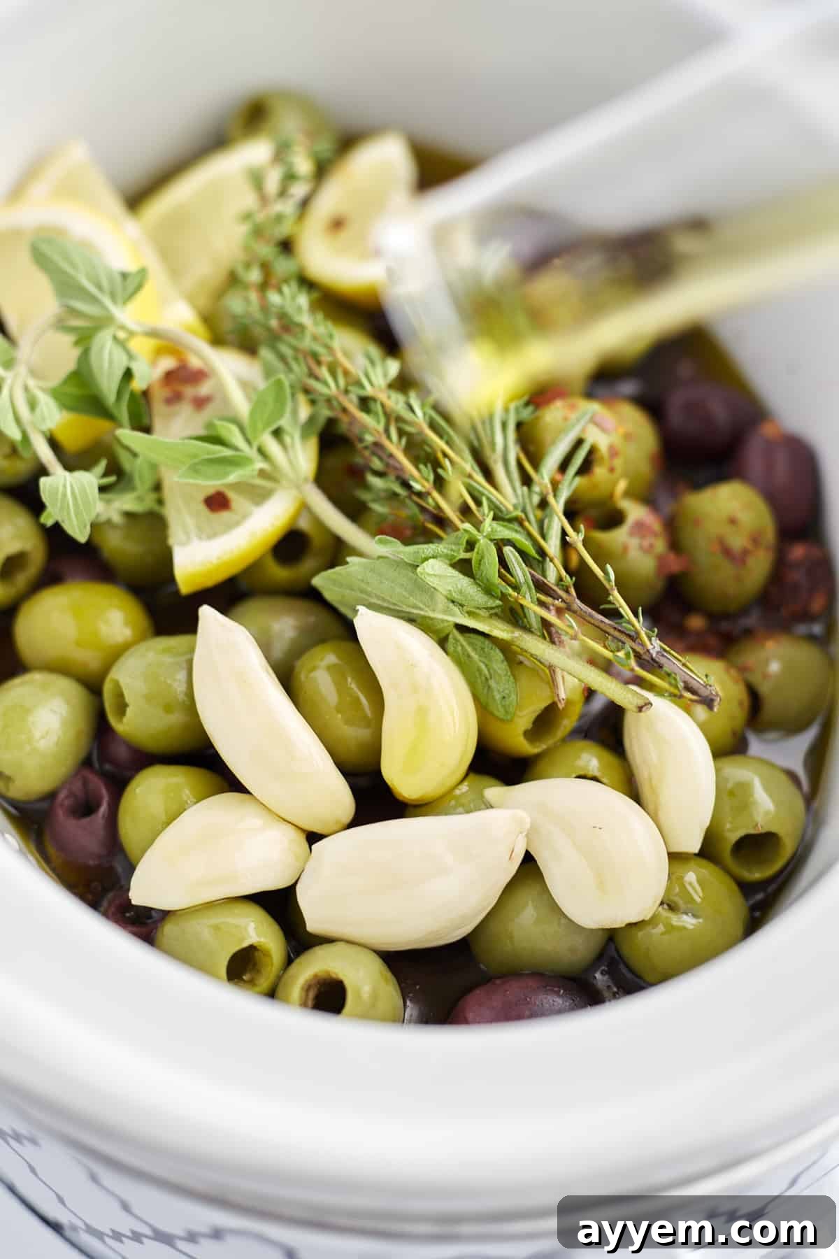 green and red olives, lemon wedges, garlic, and herbs in a slow cooker to make roasted olives