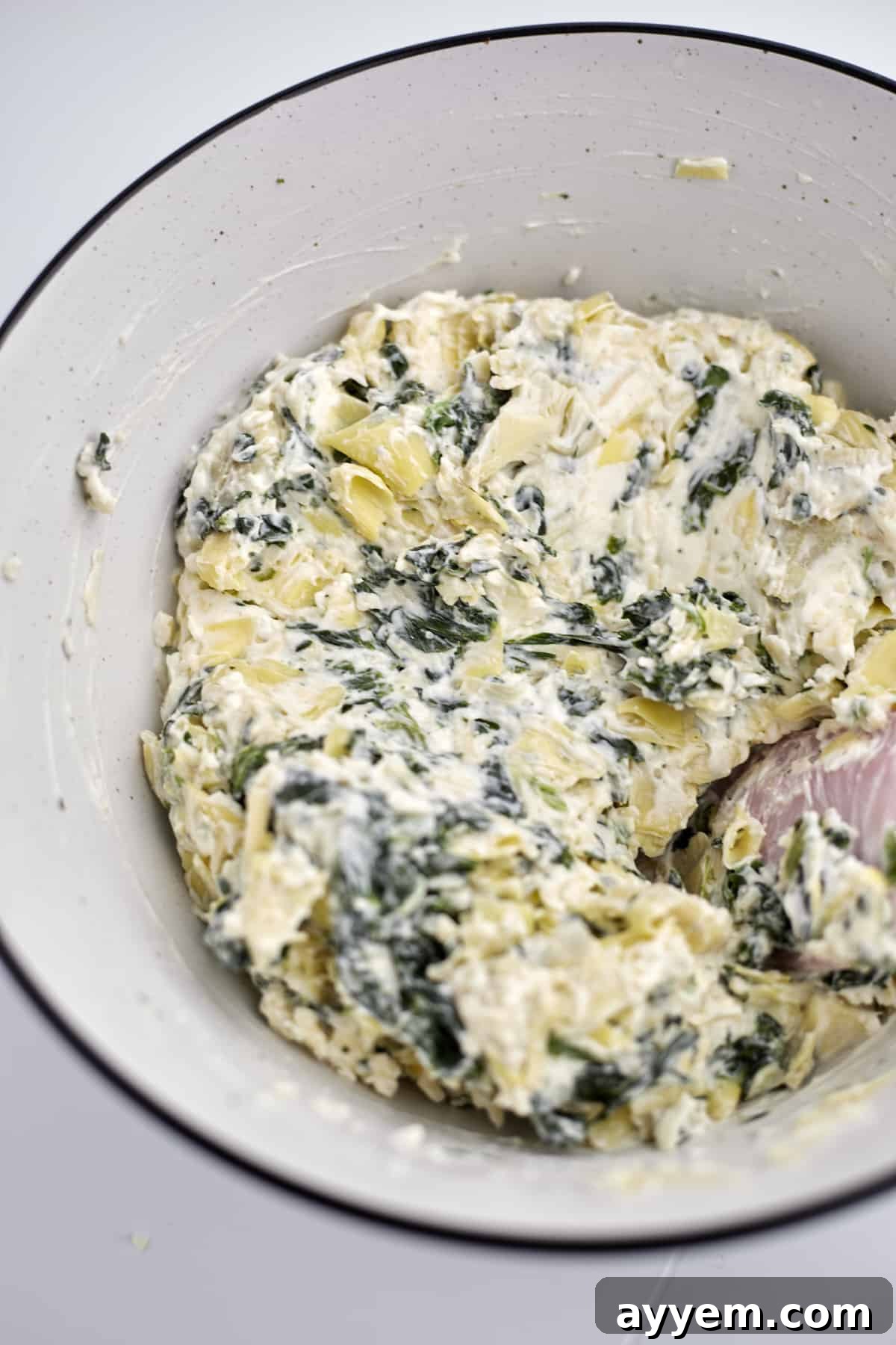 Loaded Garlic Bread with Spinach and Artichokes 3 A creamy, savory spinach and artichoke mixture in a white bowl, ready to be spread onto bread for homemade garlic bread.