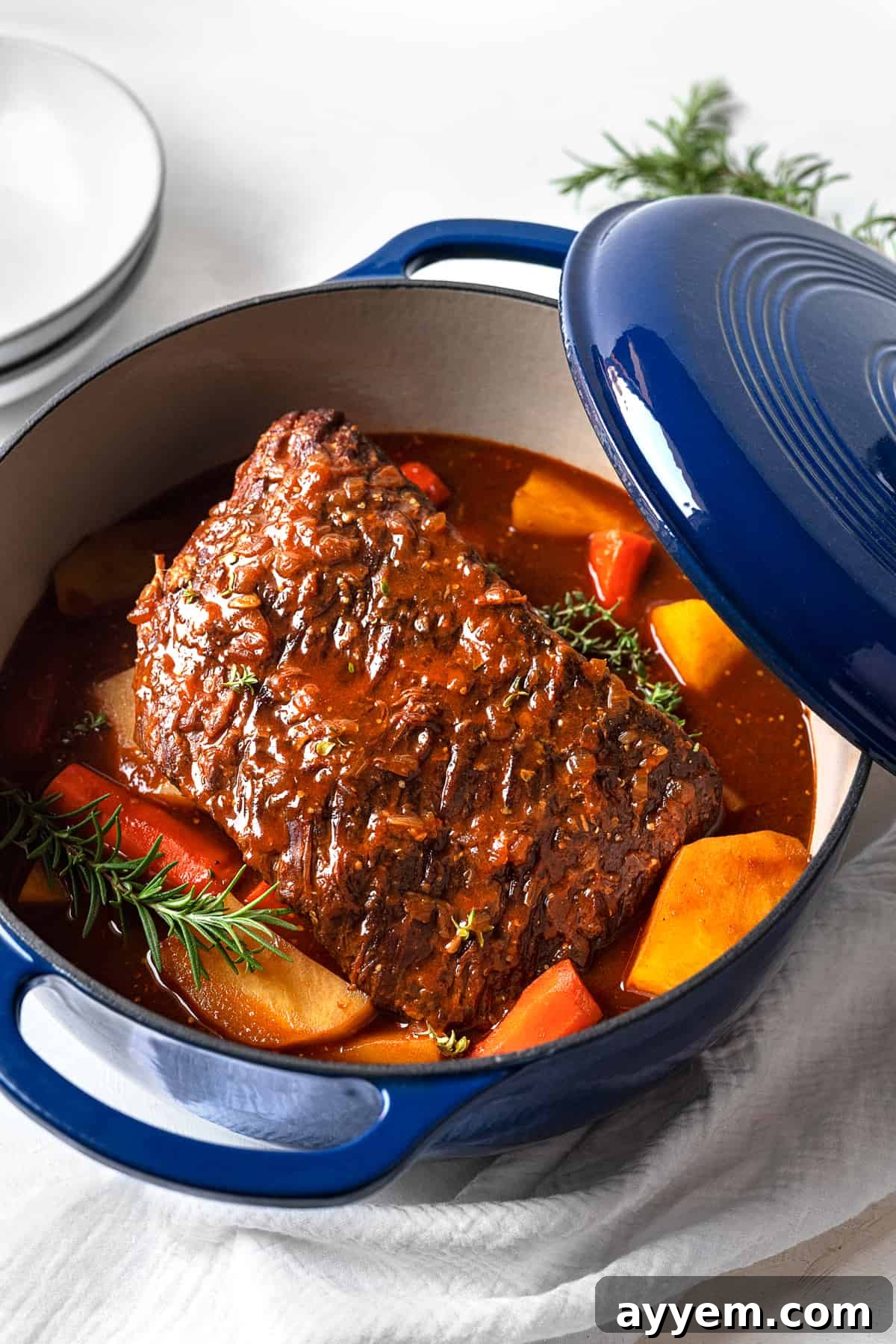 A close-up view of the cooked beef pot roast in a Dutch oven, showcasing the tender beef, golden potatoes, and vibrant carrots.