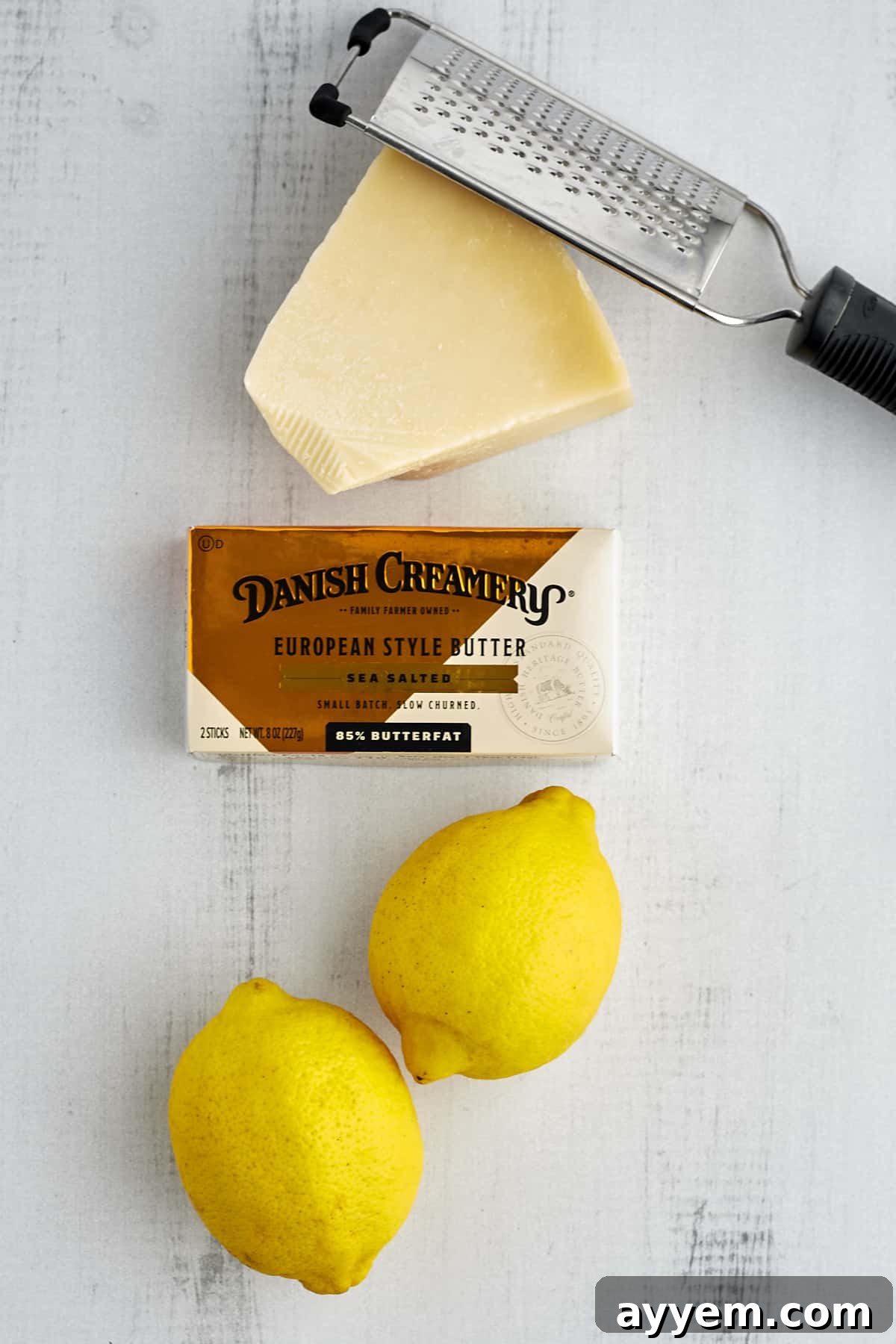 a grater, a bock of Parmesan cheese, Danish Creamery butter, and two lemons