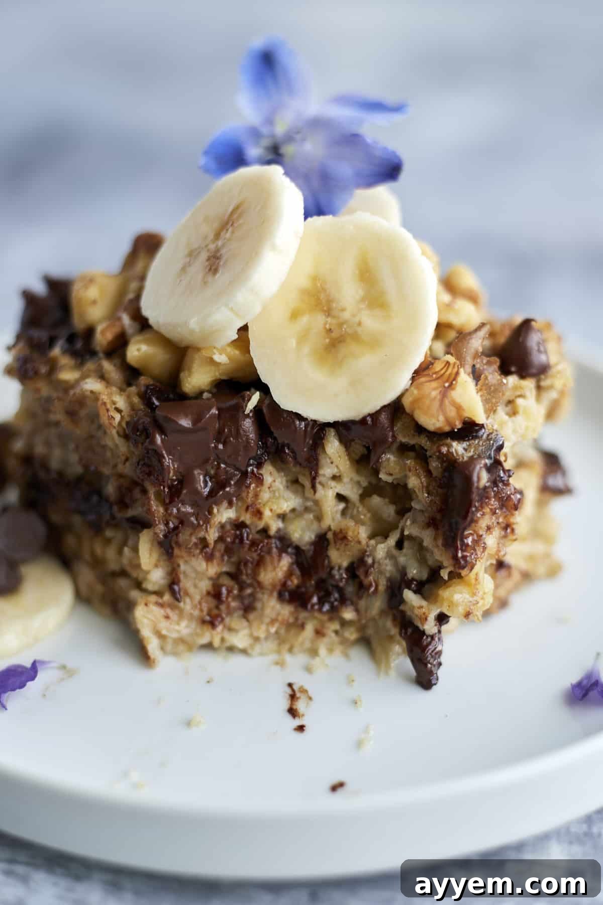 Banana Bread Oatmeal on a white plate topped with walnuts and banana coins with a bite taken out