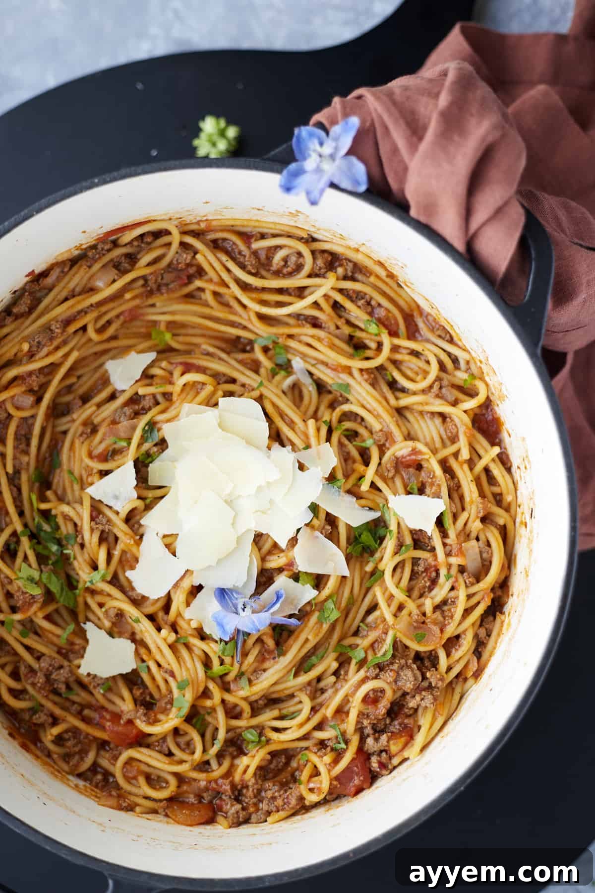 Overhead view of One-Pot Spaghetti with Ground Beef served in a large pot, garnished with freshly shaved Parmesan cheese and a sprinkle of parsley.