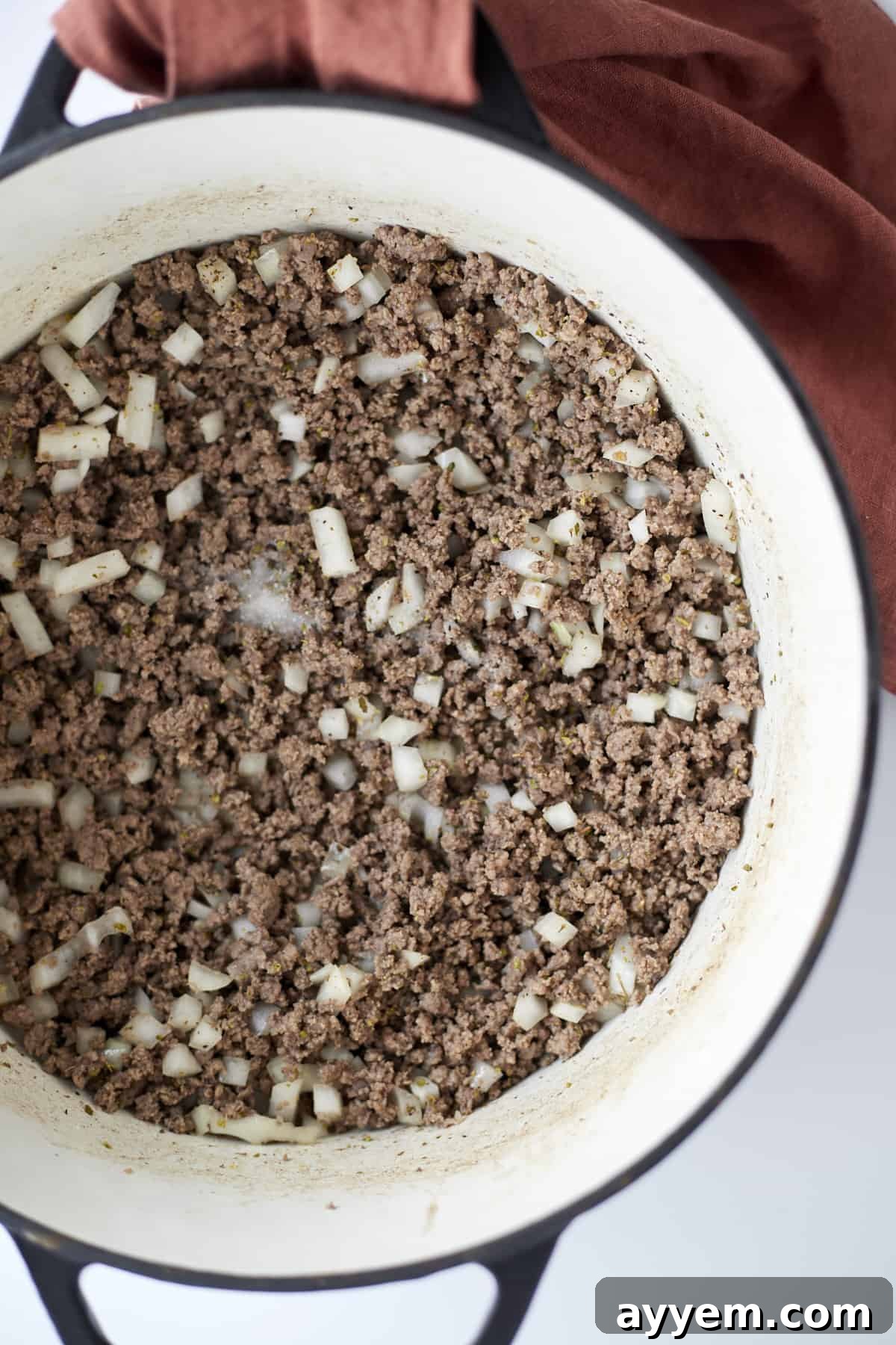 Overhead image showing cooked ground beef with chopped onions and minced garlic in a large pot, ready for the next steps of the one-pot spaghetti recipe.