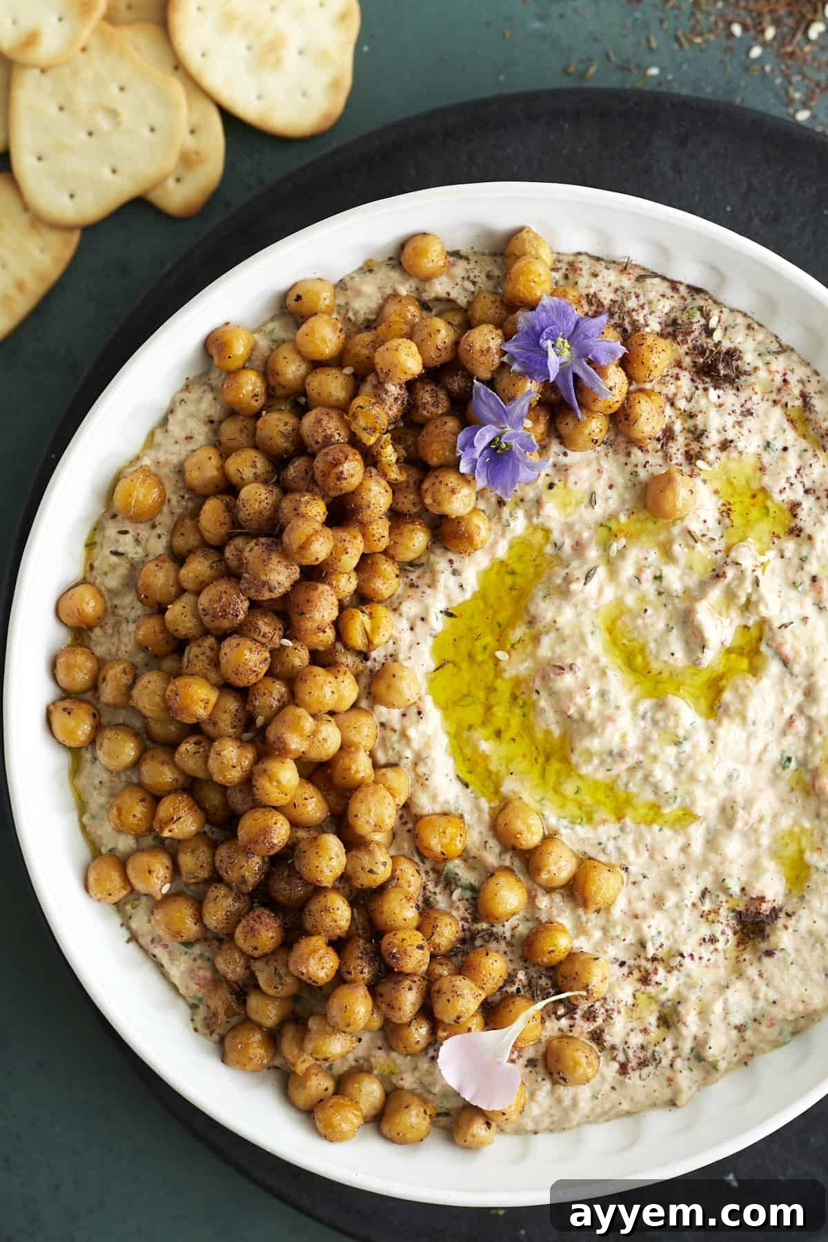 a white bowl full of an easy baba ganoush recipe topped with crispy chickpeas and olive oil
