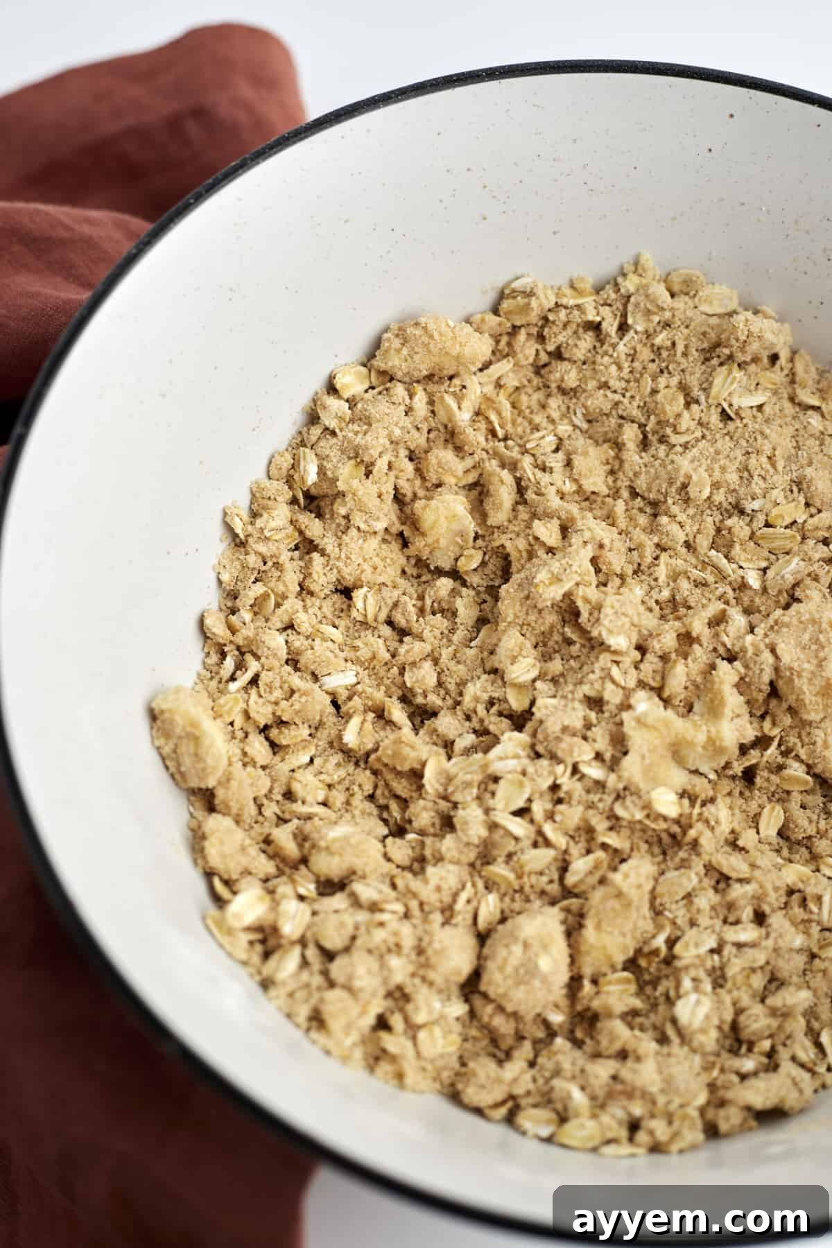 Delightfully Simple Peach Crisp 6 Close-up image of a white mixing bowl filled with the dry ingredients for the oat and flour crisp topping, ready to be combined with butter.