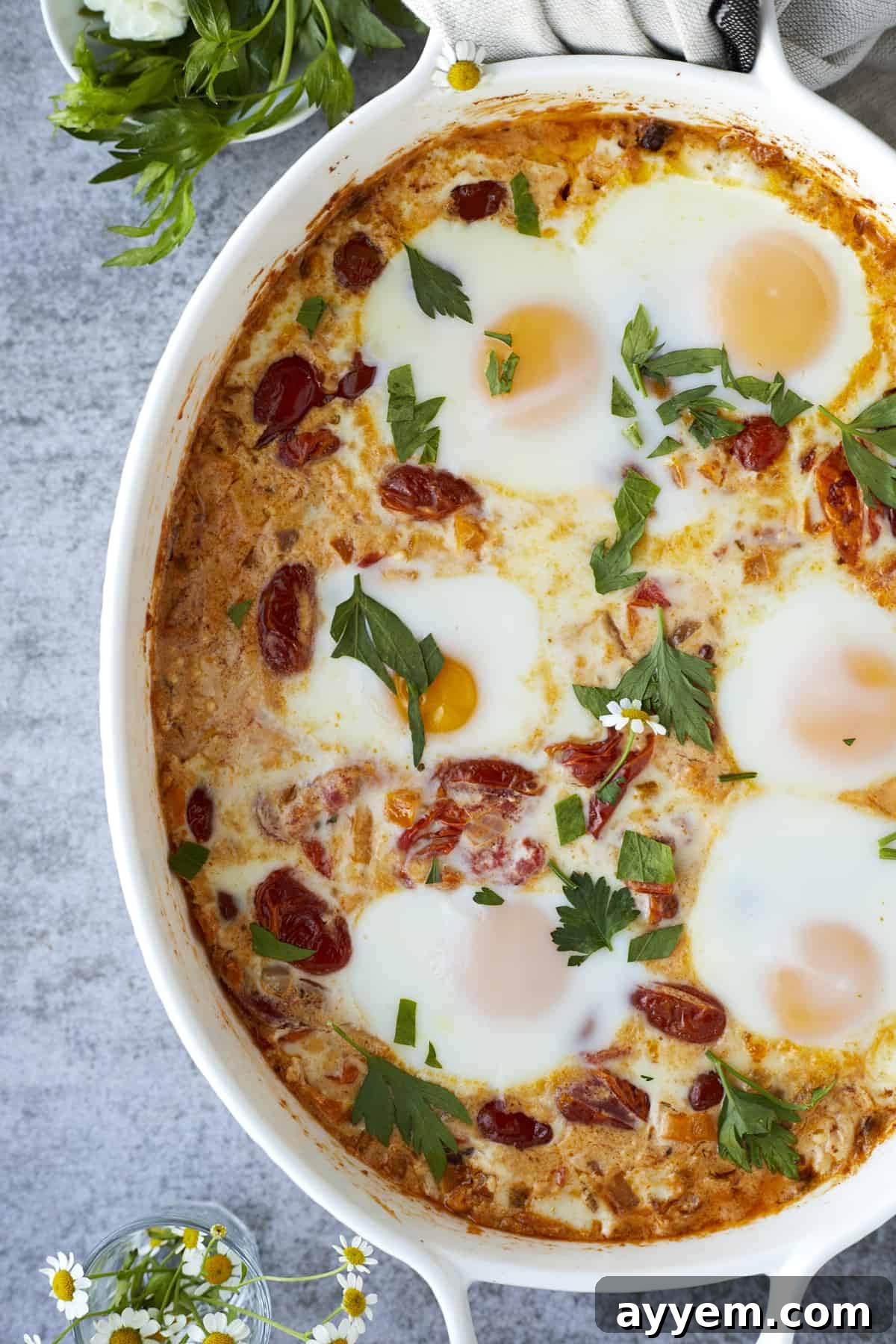 close up image of oven baked eggs with feta and veggies topped with fresh herbs.