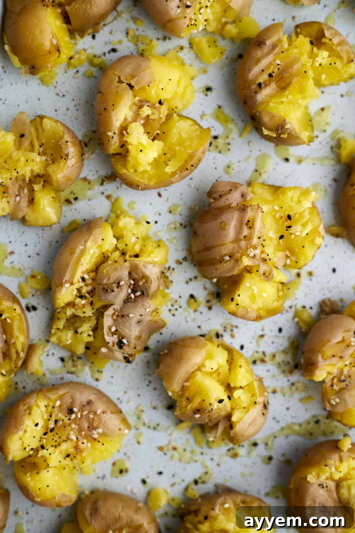 The Ultimate Crispy Smashed Potatoes 3 Boiled smashed potatoes on a baking sheet topped with everything but the bagel seasoning.