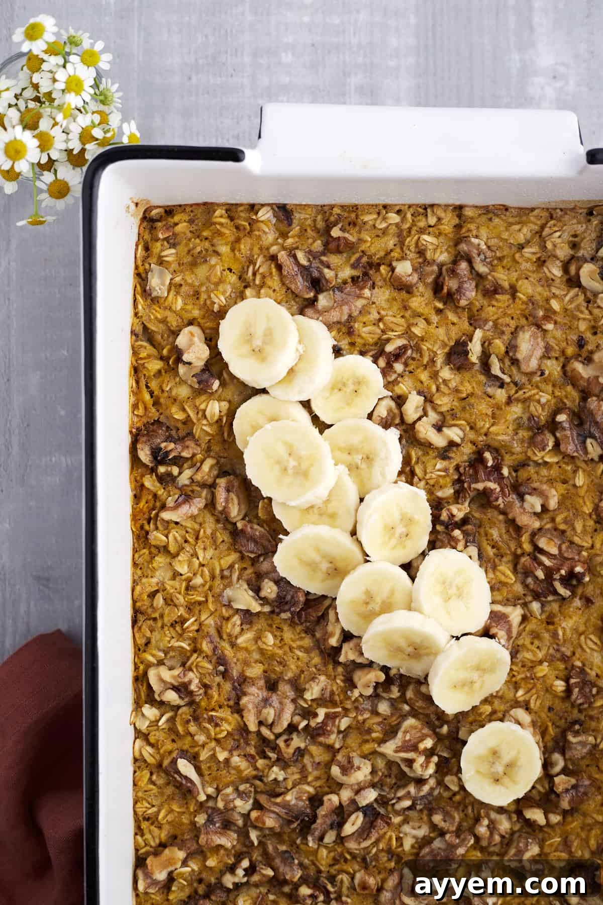 Overhead image of baked pumpkin oatmeal topped with pecans and banana coins.