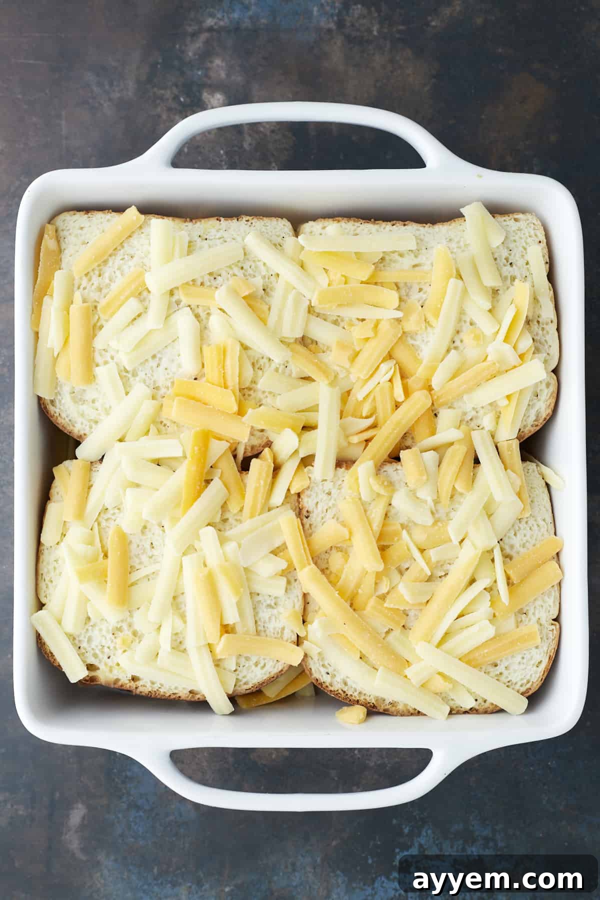 four unbaked fajita chicken sandwiches topped with shredded cheese in a white square baking dish