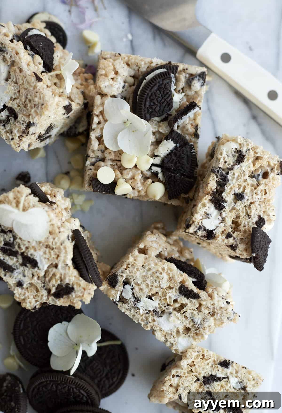 Six delicious Oreo Rice Krispie Treat squares, adorned with extra Oreo chunks and delicate white chocolate chips, presented on a light surface.