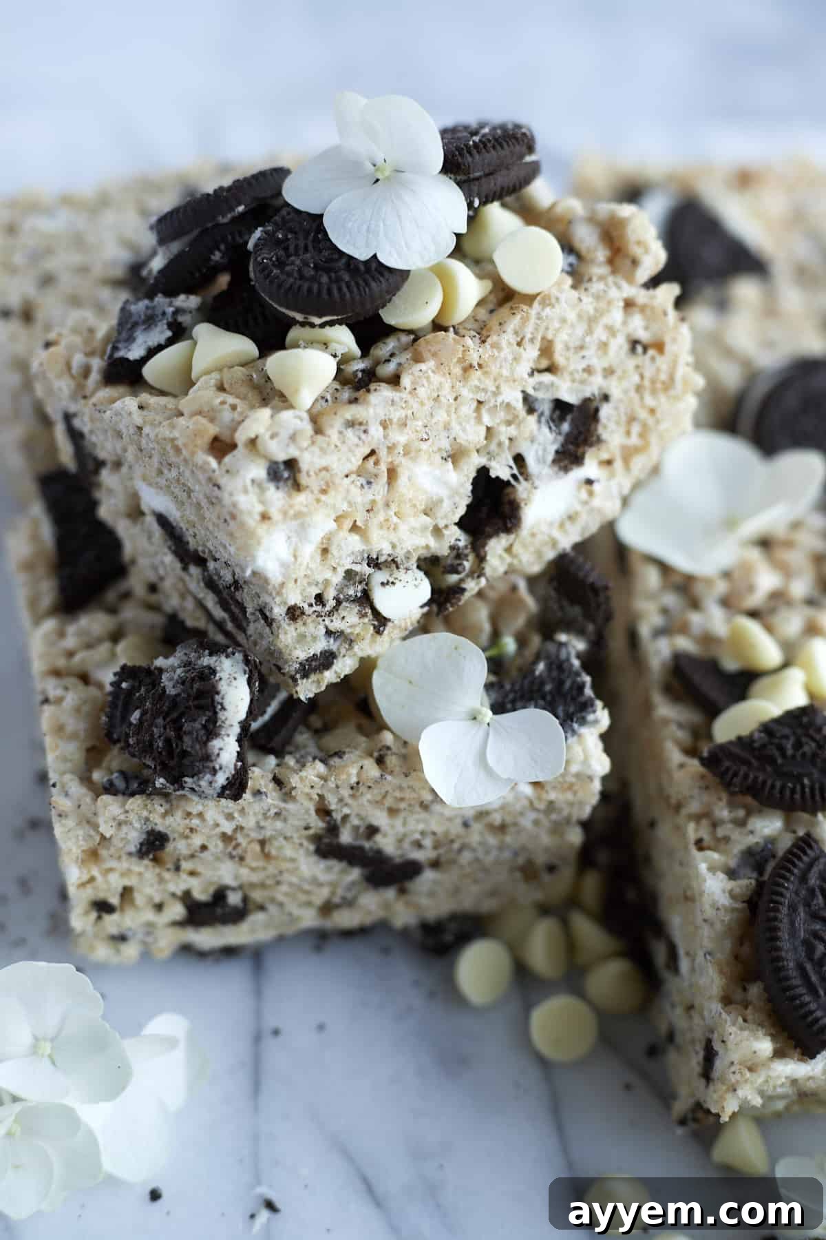 A close-up view of a perfectly cut Oreo Rice Krispie Treat, revealing its layered texture with gooey marshmallow, crispy cereal, and crunchy Oreo pieces, topped with more cookie chunks.