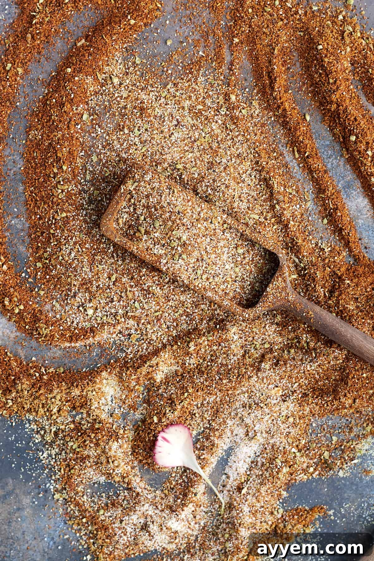 A close-up of the homemade taco seasoning blend in a bowl with a small wooden scoop.