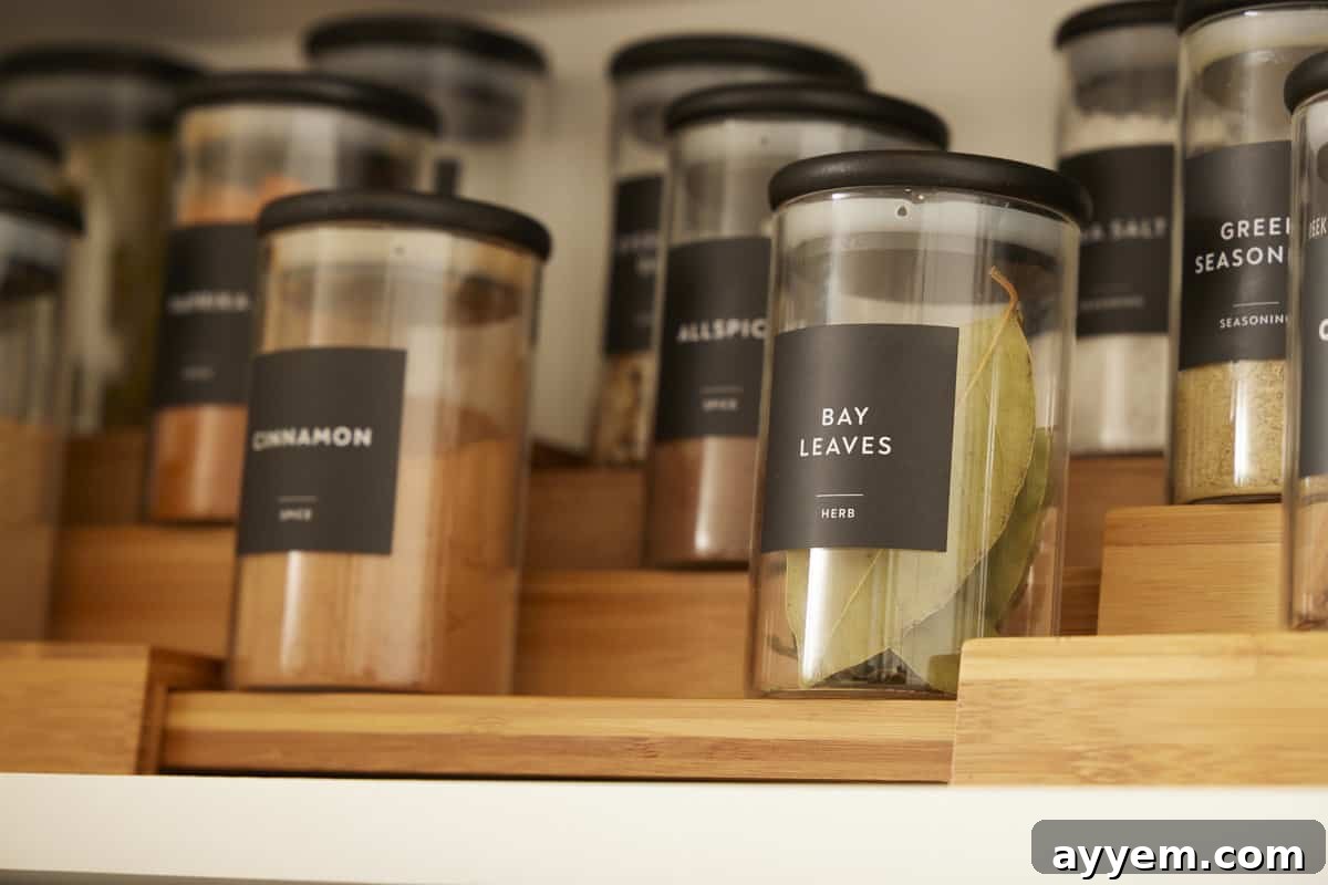 A close-up view of clear, uniformly labeled spice jars neatly arranged in a cabinet, showcasing a pristine organization system.