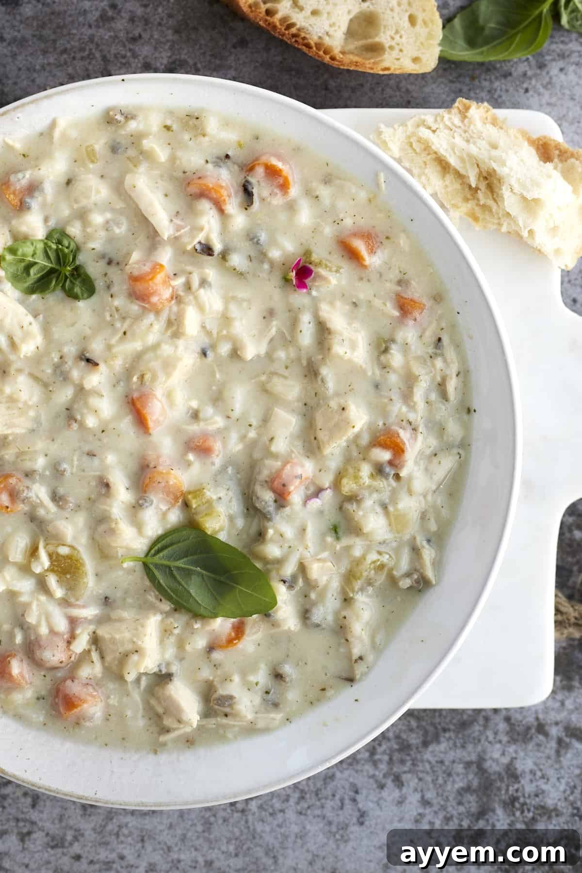 creamy chicken wild rice soup in a bowl with a chunk of bread on the side