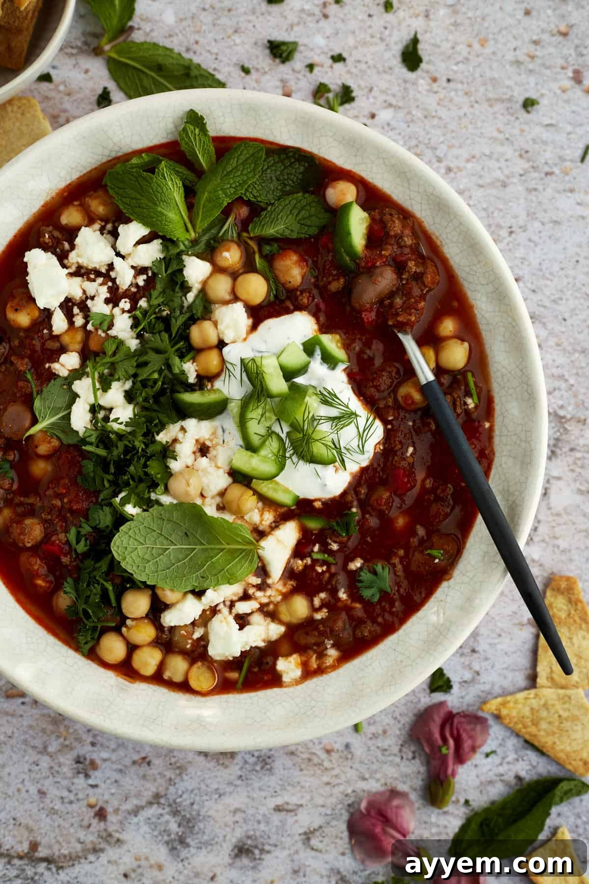 A vibrant bowl of Middle Eastern beef chili, garnished with fresh herbs and a swirl of yogurt, ready to be enjoyed.