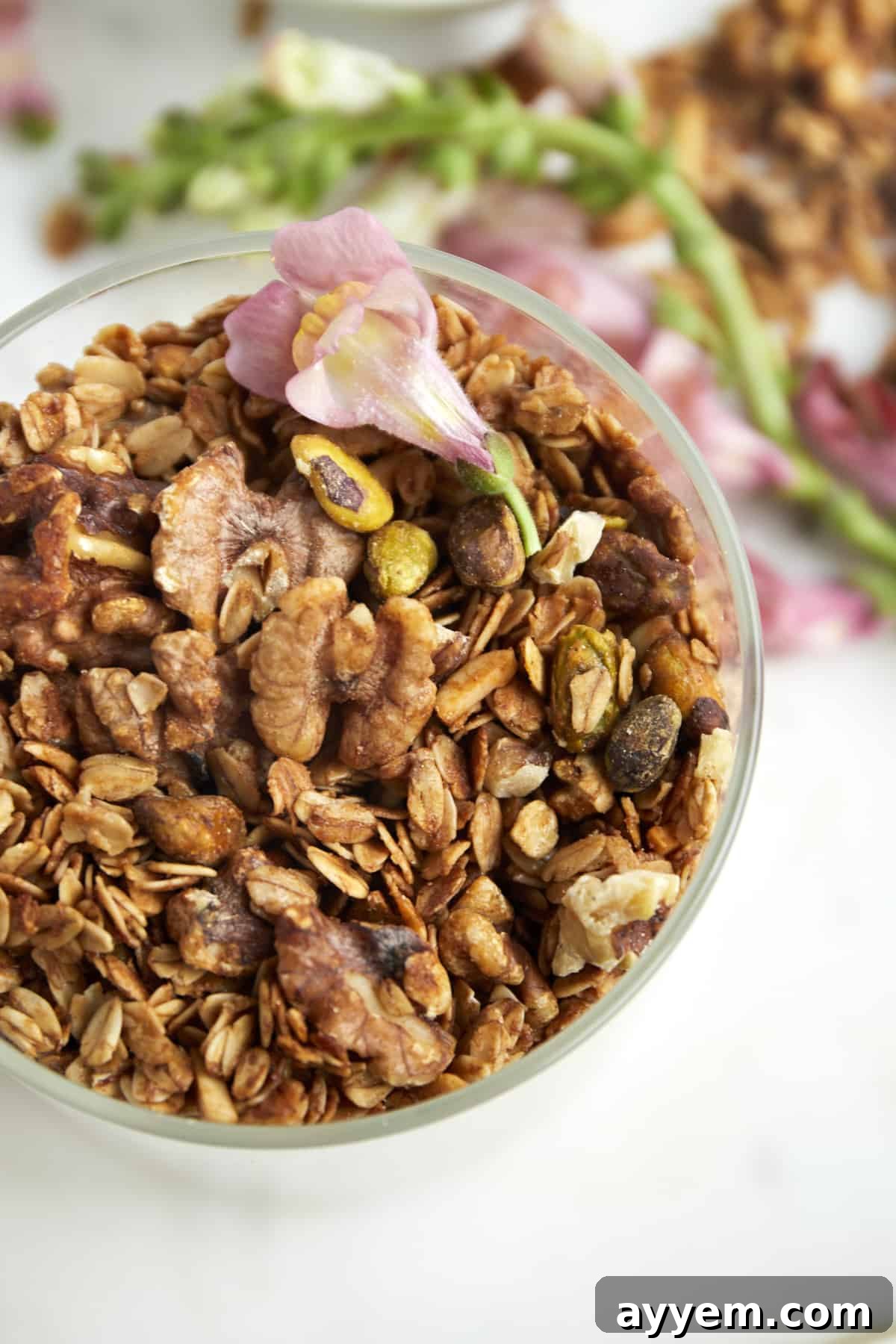 An overhead view of a glass jar filled with Baklava Granola, showcasing its appealing texture and nutty inclusions.