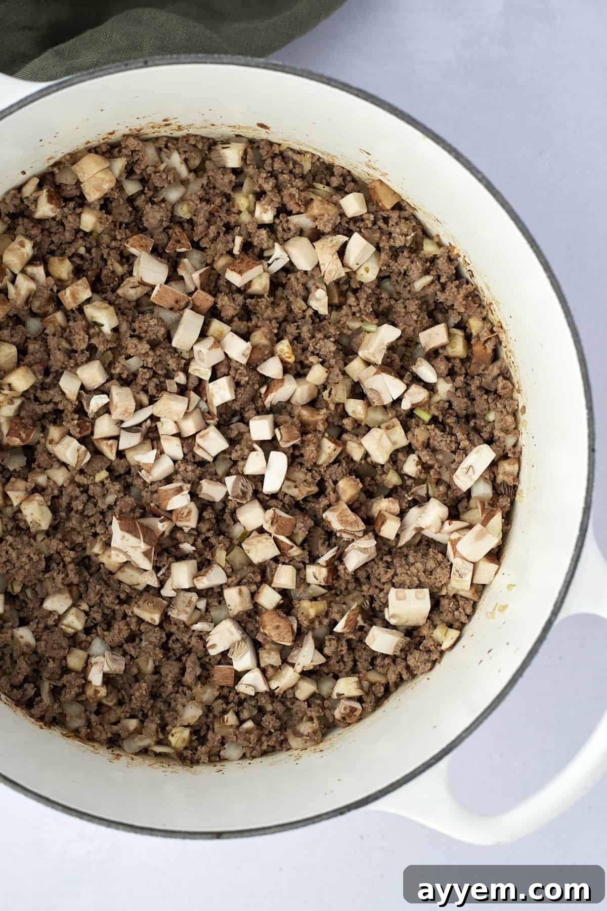 Browned ground beef, onions, and mushrooms in a pot, ready to form the base of a tater tot hotdish recipe