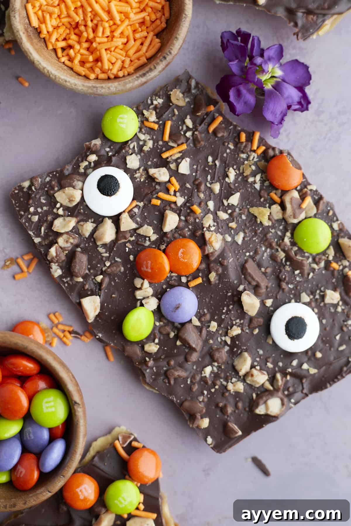 two pieces of Halloween saltine crack candy decorated with toffee, M&Ms, and candy eyeballs
