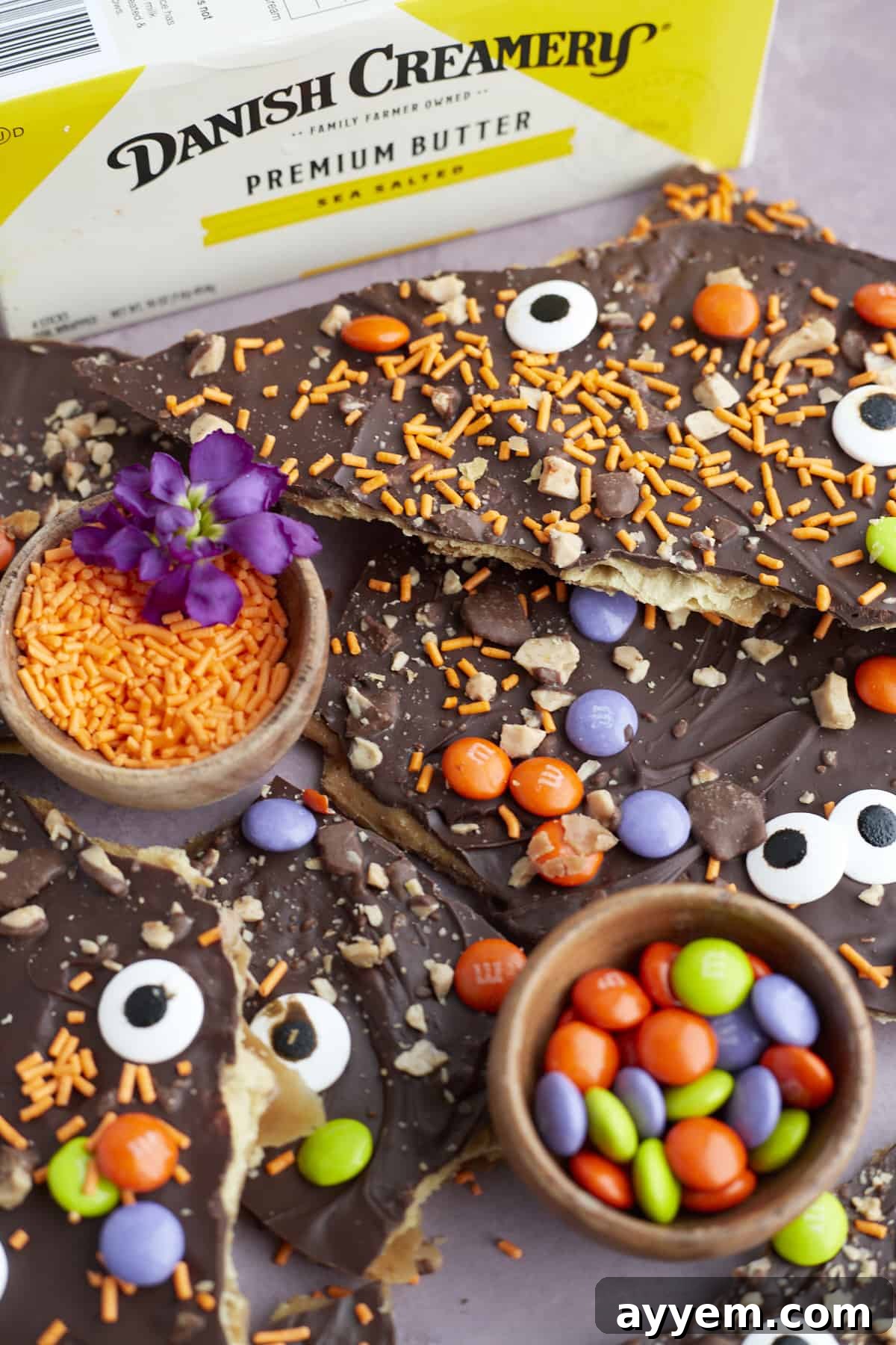 pieces of Halloween saltine crack candy with small bowls of m&ms and orange sprinkles in between 