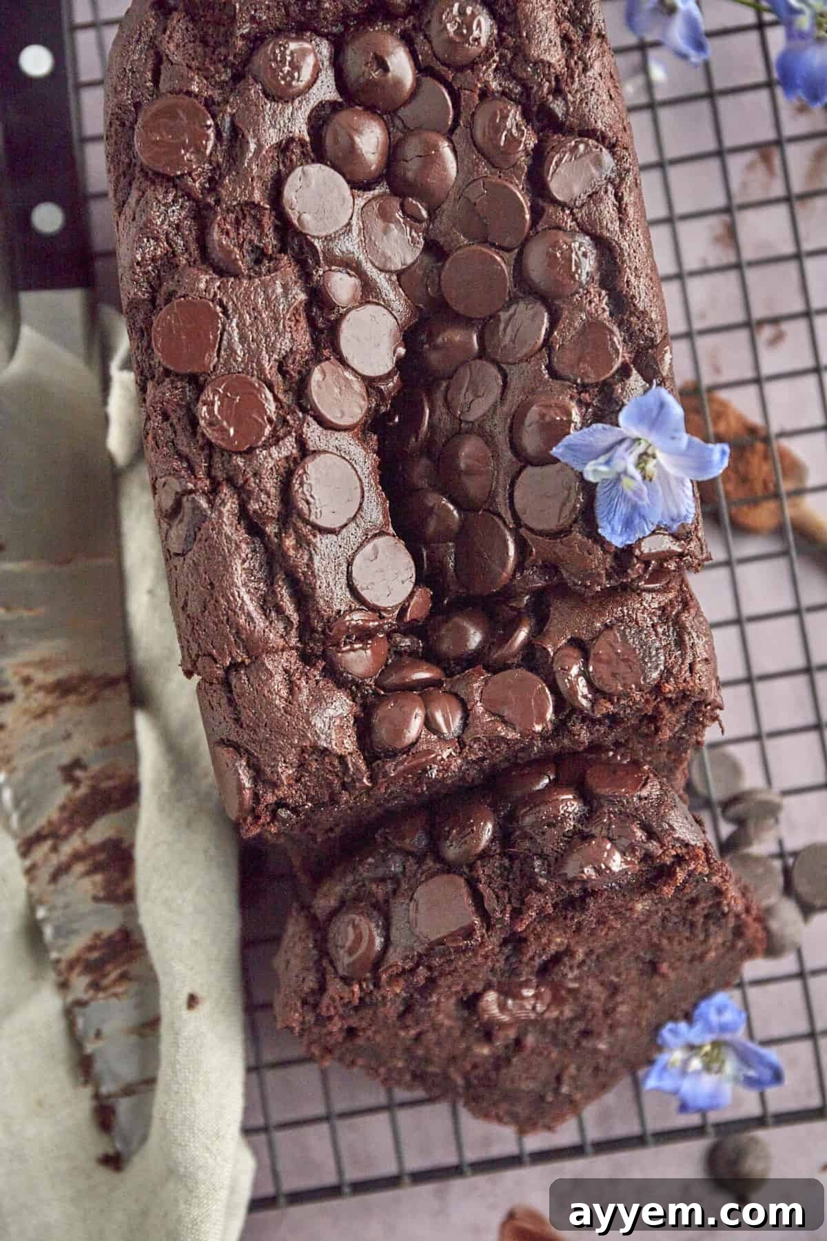 a loaf of double chocolate banana bread on a wire rack with one slice cut