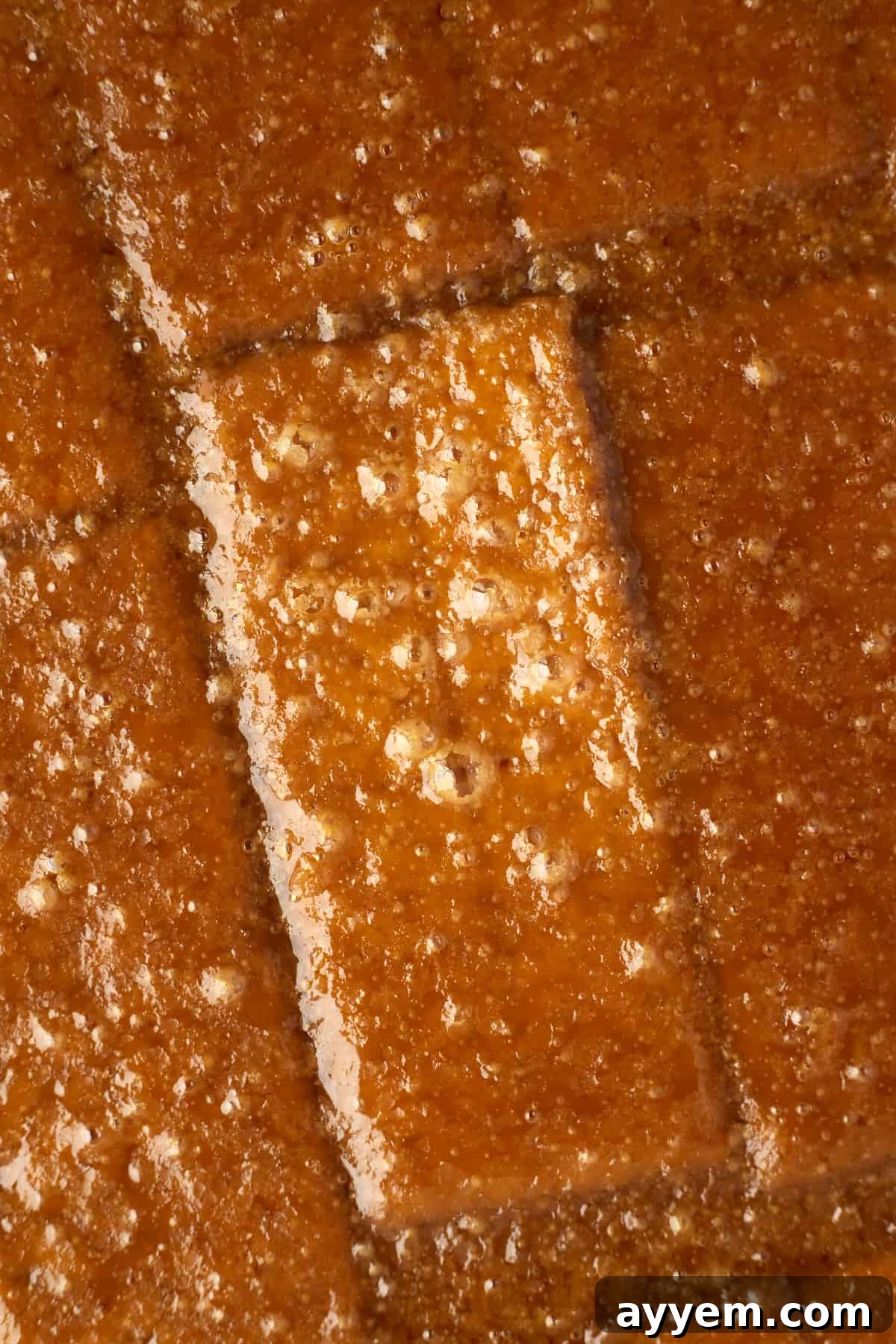 Melted toffee perfectly spread over a single layer of graham crackers on a baking sheet, ready for the next step of chocolate and toppings.