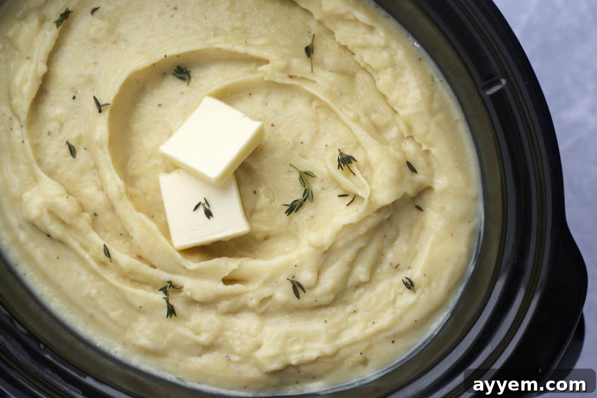 Luxuriously creamy mashed potatoes, still in the slow cooker, glistening with melted butter and ready to be served.