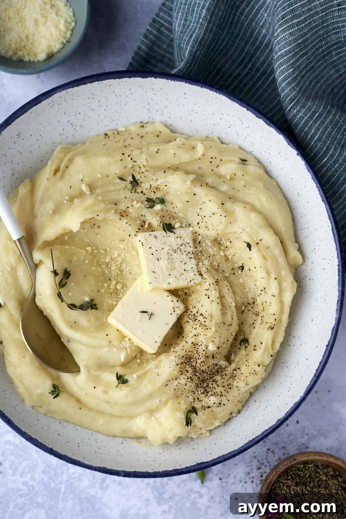 A beautifully presented bowl of creamy slow cooker mashed potatoes, topped with melting butter, a sprinkle of fresh herbs, and cracked black pepper.