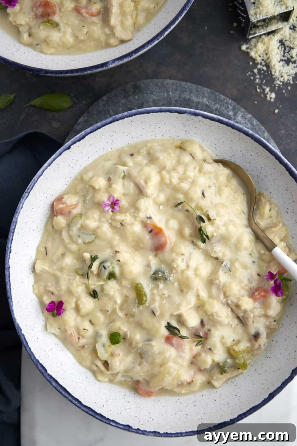 An overhead view of a white bowl filled to the brim with creamy chicken noodle soup, ready to be enjoyed.