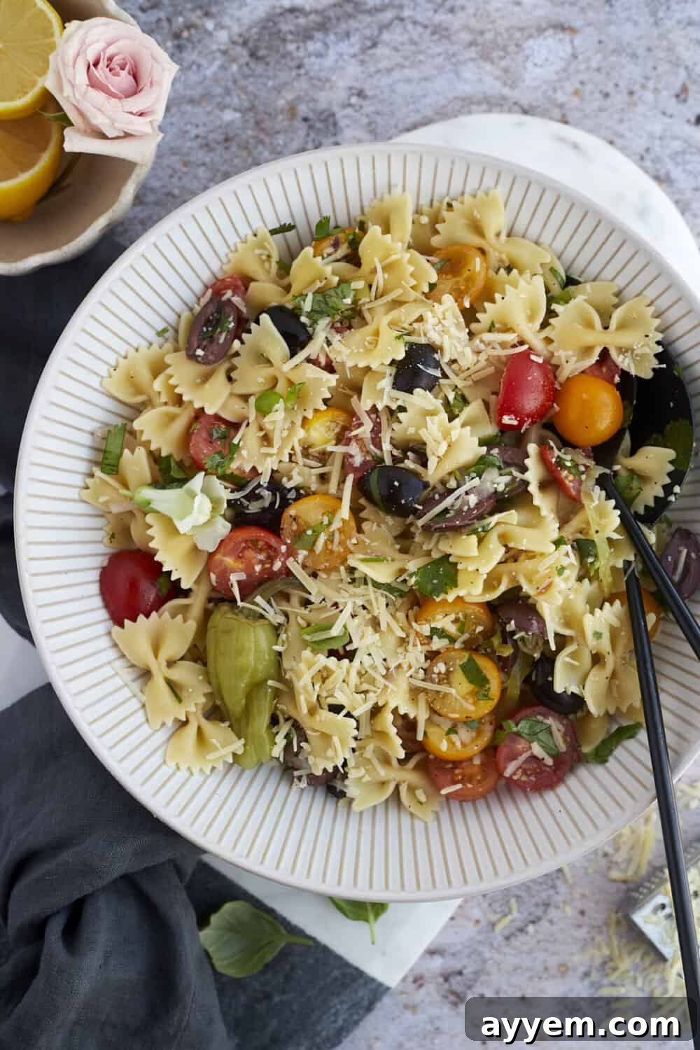 Warm Italian pasta salad in a large serving bowl with serving tongs on the side, ready to be enjoyed.