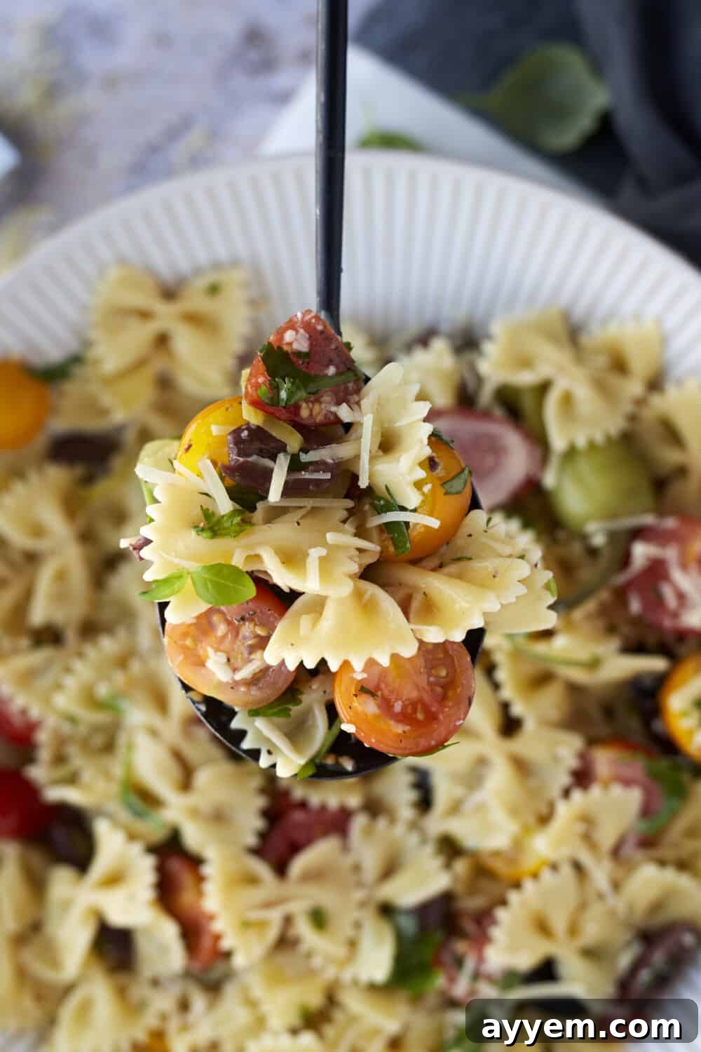 Close-up image of warm Italian pasta salad on a spoon, highlighting the rich texture and vibrant ingredients.