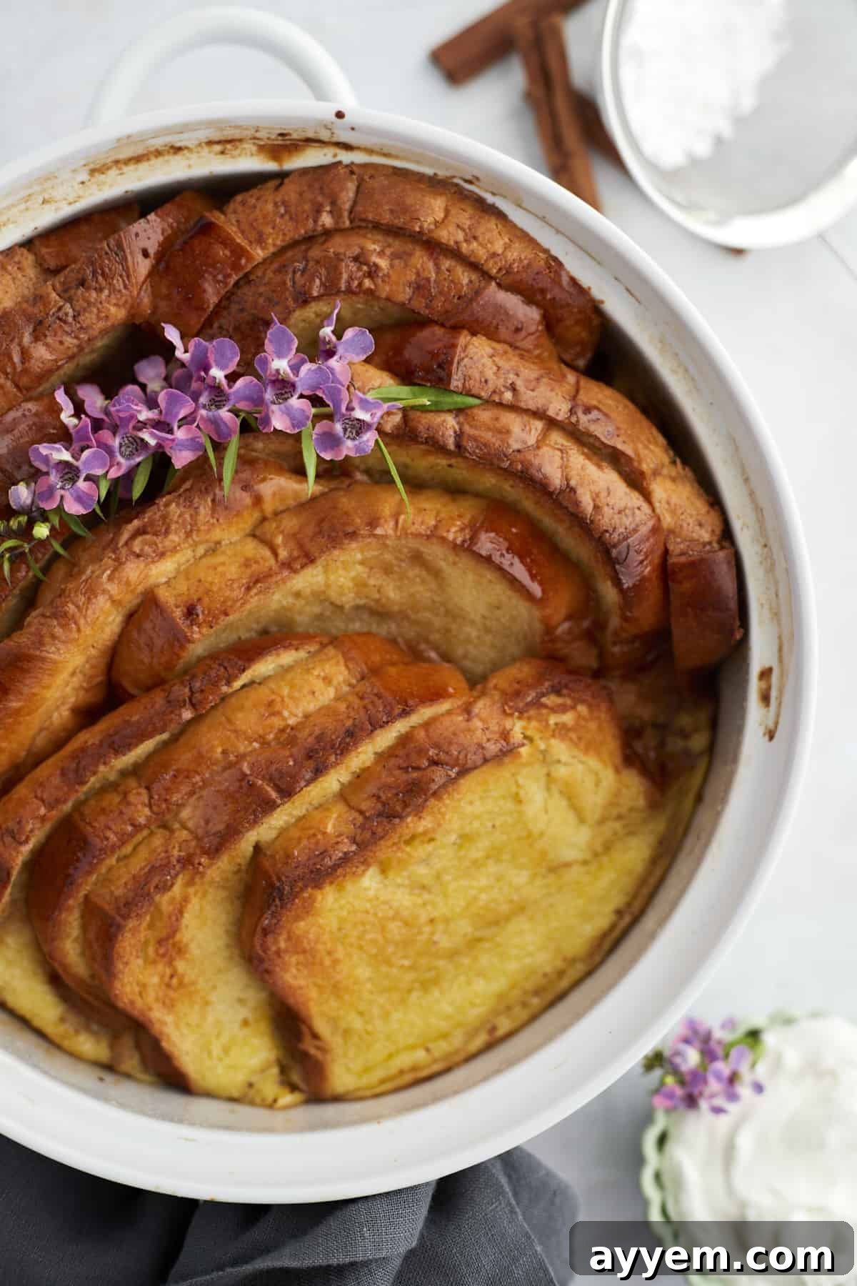 A beautifully baked cinnamon French toast casserole in a white dish, fresh out of the oven, ready to be topped and served.