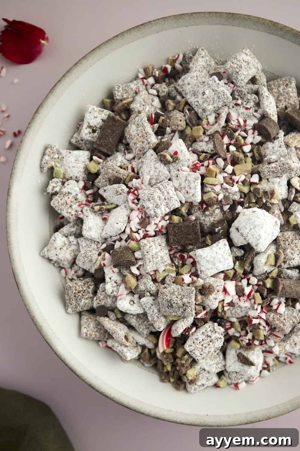 a bowl of Christmas puppy chow with dark chocolate chunks, Andes mints, and peppermint pieces.