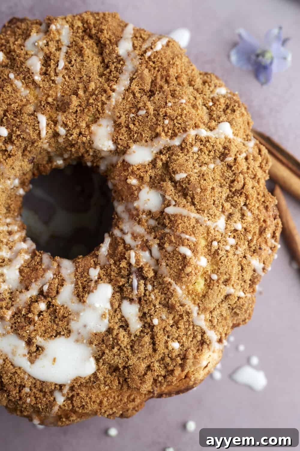 An overhead view of a complete sour cream coffee cake, beautifully topped with a delicate powdered sugar glaze, ready to be sliced and served.