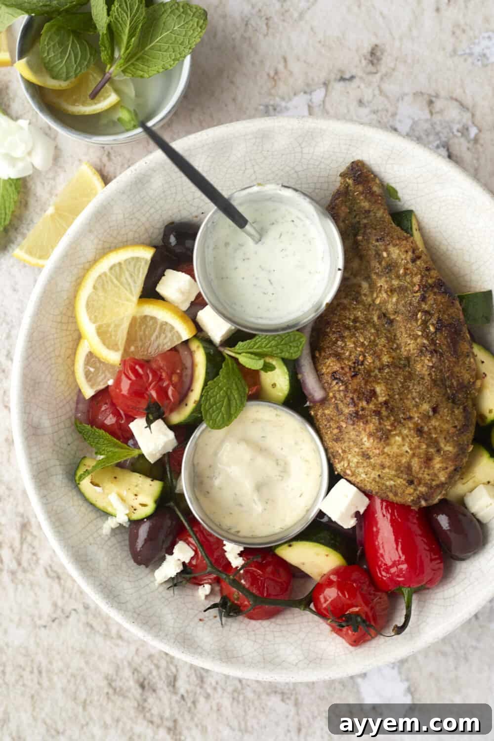a bowl of za'atar chicken with vegetables and dipping sauce