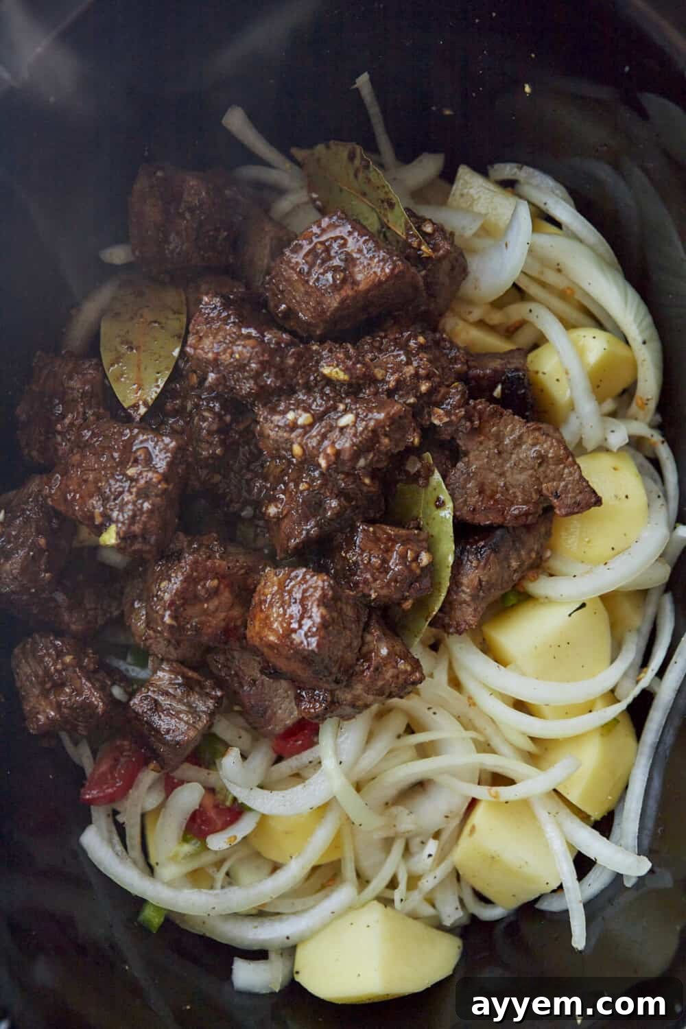 seared beef, onions, potatoes, and spices in a crock pot.