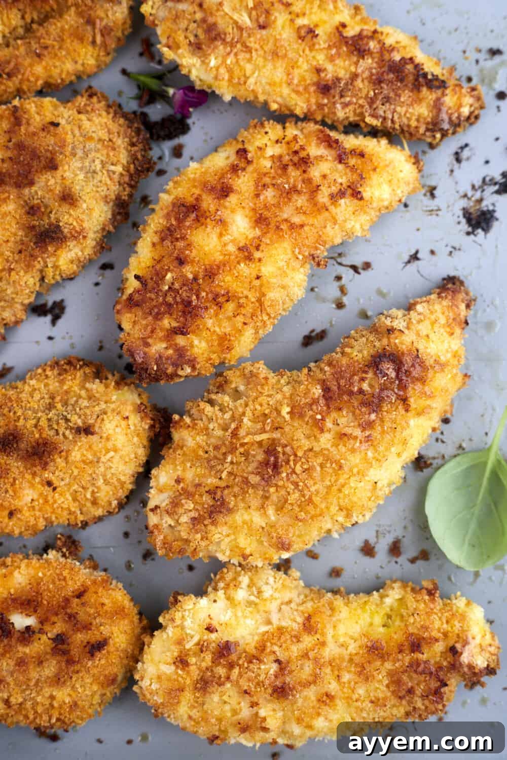 Freshly baked parmesan chicken tenders arranged on a baking sheet, ready to be served.
