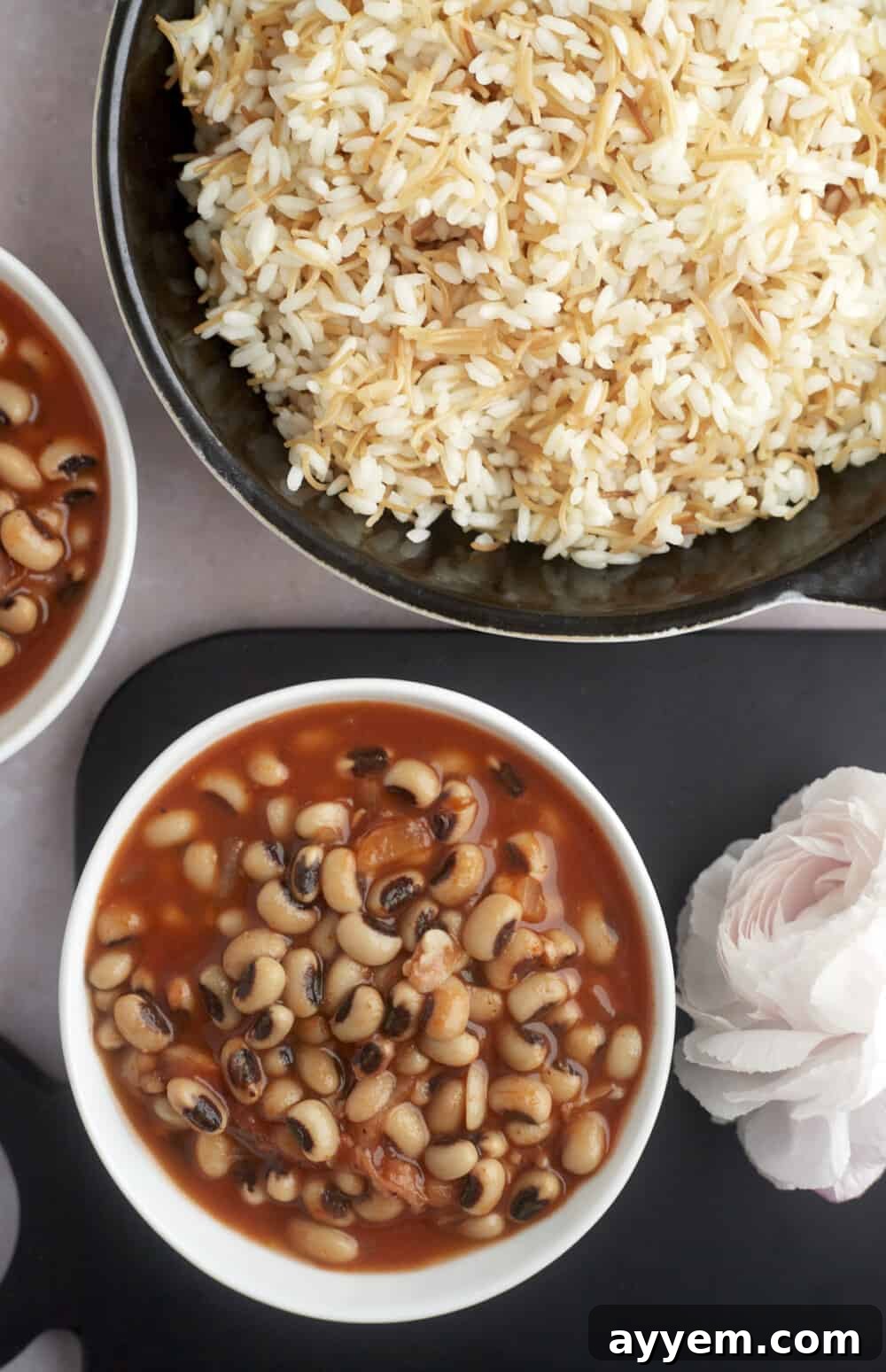 bowls of hearty black-eyed pea stew alongside a large pot of vermicelli rice, ready to serve
