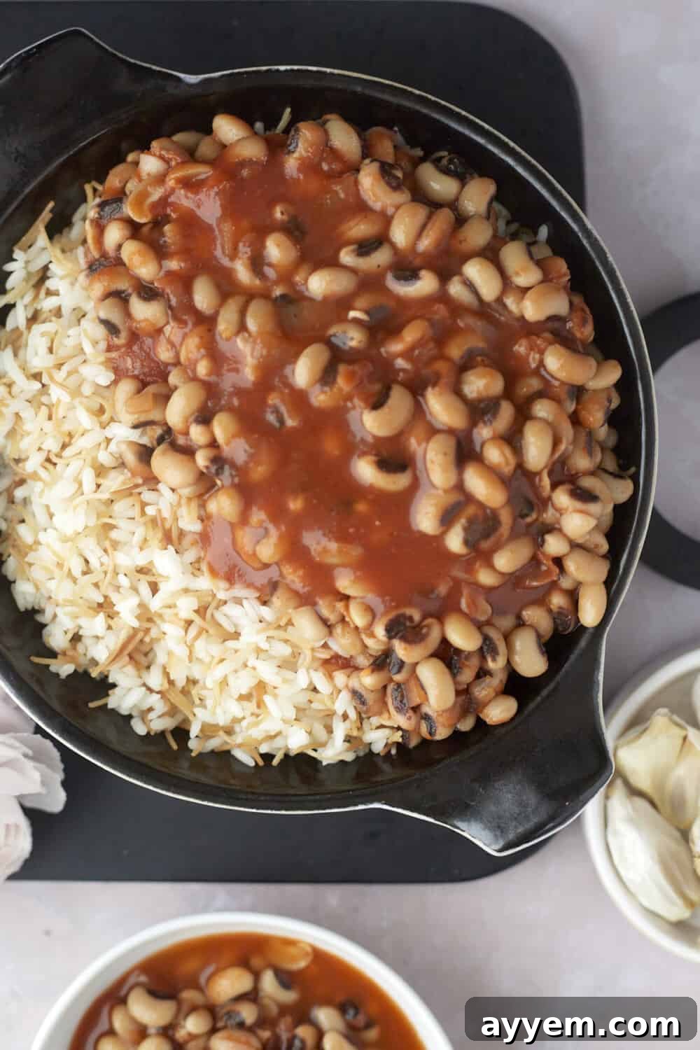 overhead view of vermicelli rice topped with a generous serving of black-eyed pea stew in a skillet