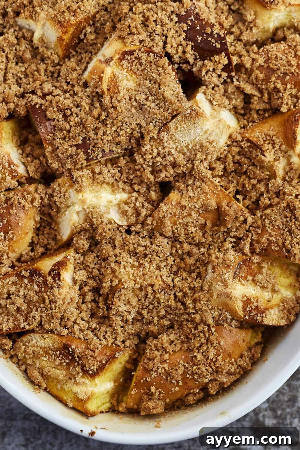 Close-up of Cinnamon Crunch Bagel French Toast Casserole with a spoon, highlighting its crumb topping and moist interior.