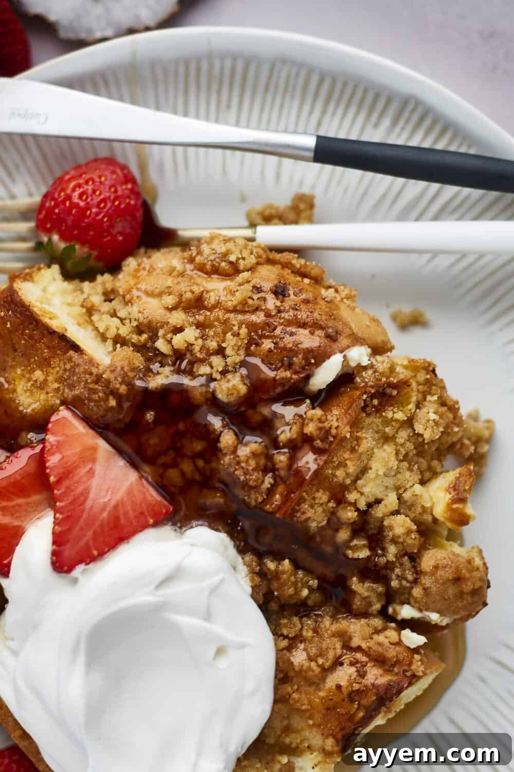 A slice of Cinnamon Crunch Bagel French Toast Casserole drizzled with maple syrup, showcasing its delicious layers.