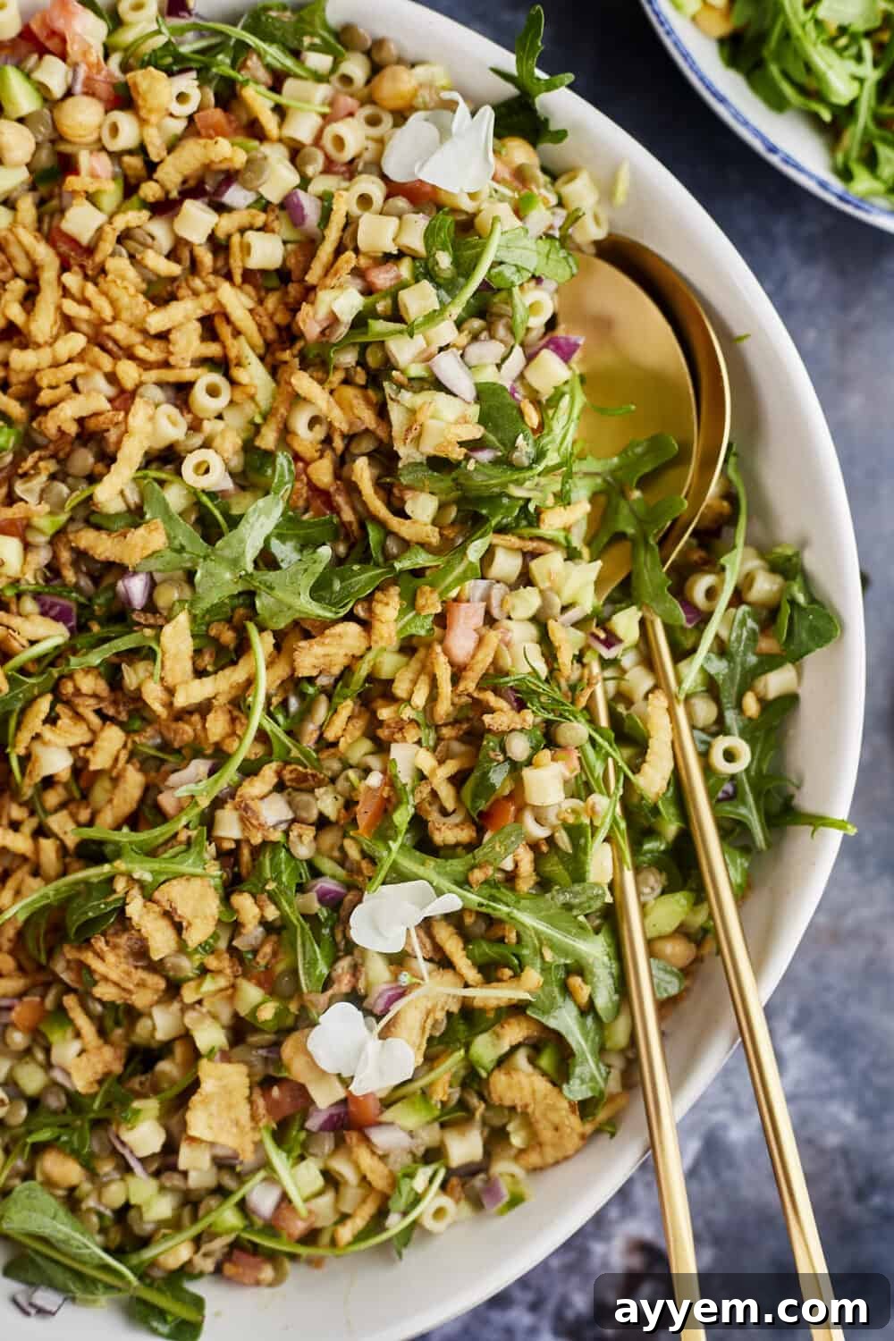 A large serving bowl of Chickpea and Lentil Salad, garnished with fresh herbs and a drizzle of dressing, ready to be served.