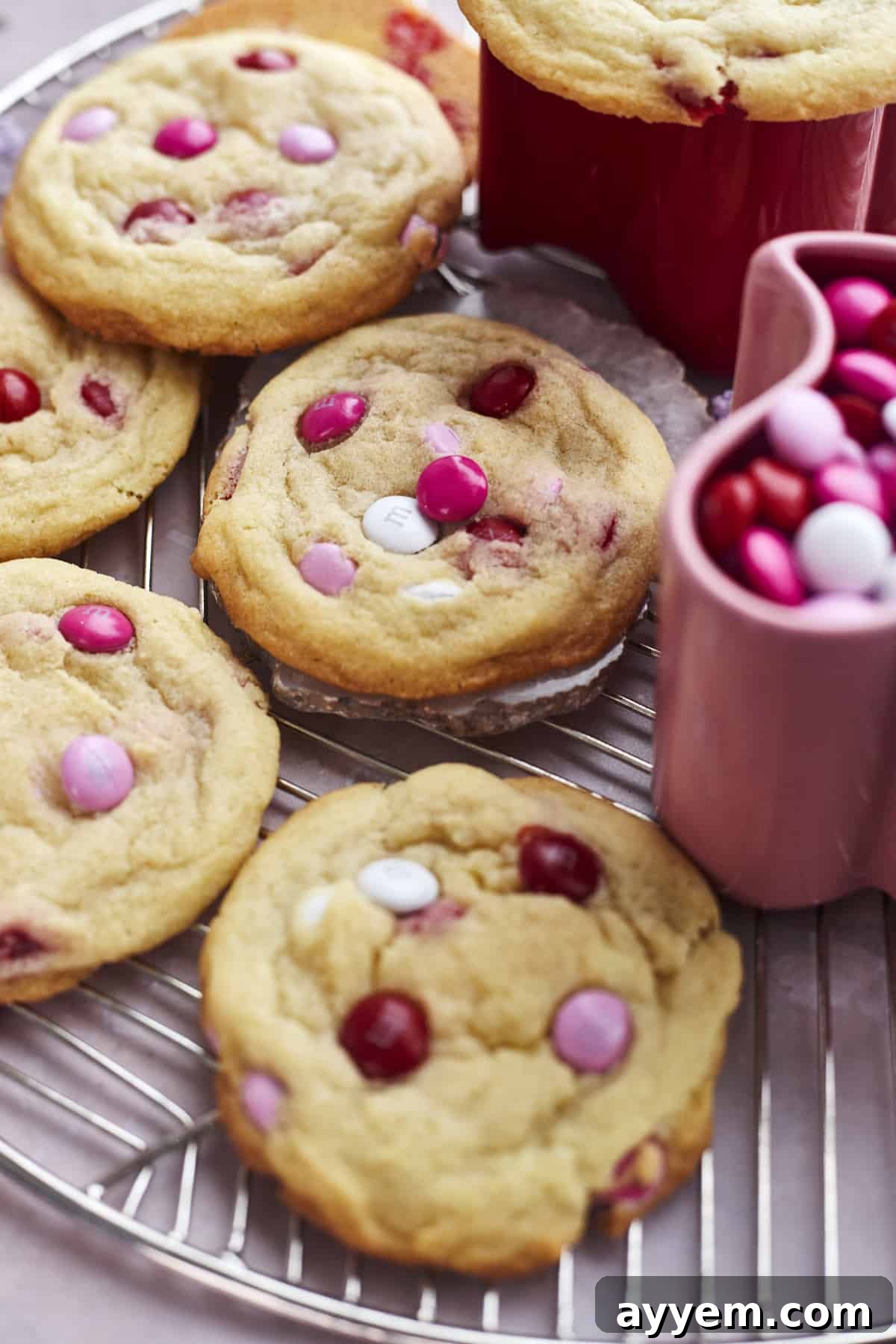 Valentine's M&M sugar cookies stacked next to a cup of M&Ms
