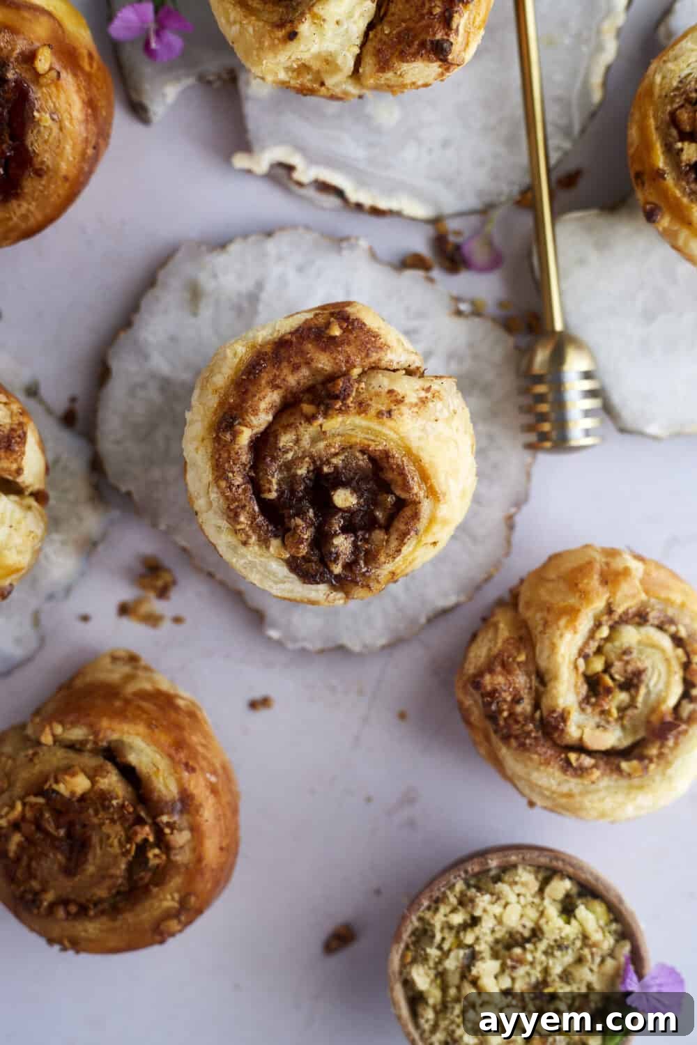 Close up of a single Baklava Puff Pastry Cinnamon Roll, flaky and golden brown, with honey glistening.