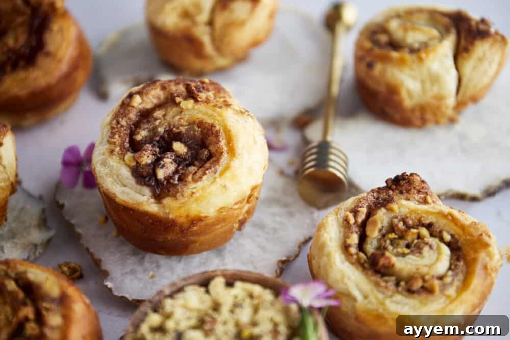 Two hands holding a plate with a single Baklava Puff Pastry Cinnamon Roll, highlighting its flaky layers.